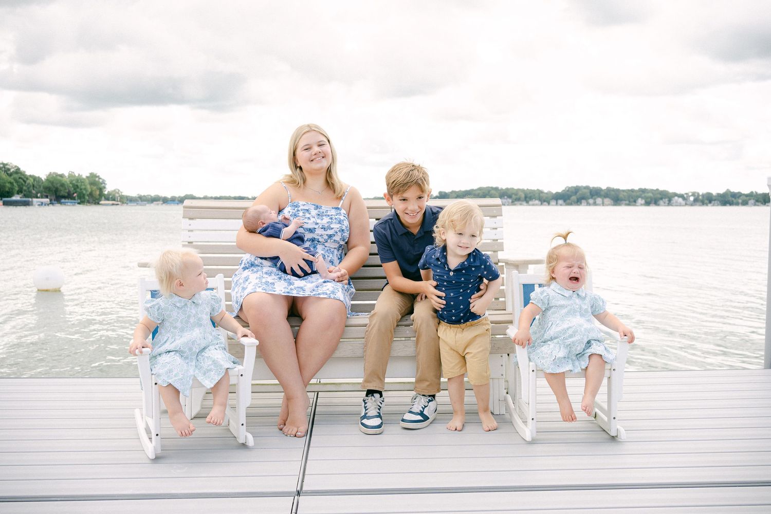 Candid moments of family fun as they sit and play together on a lakeside dock in matching casual attire.