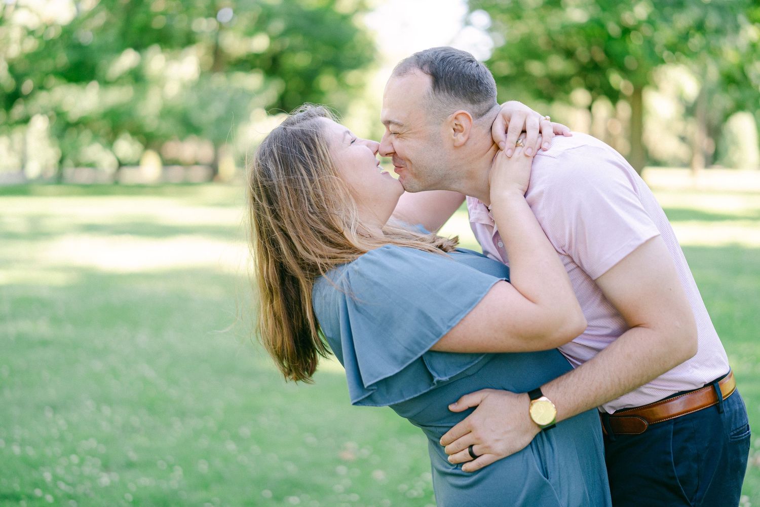 Intimate family photos captured in a sun-dappled park setting with soft natural lighting.