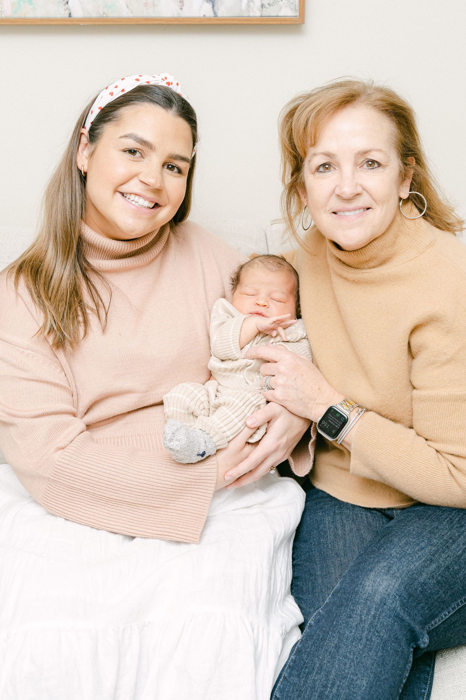 Three generations share a warm moment together while wearing cozy sweaters in neutral tones.