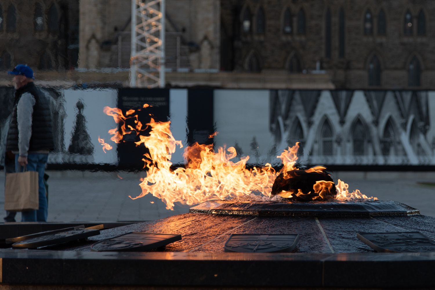 Eternal flame memorial burns brightly at night against a dark urban backdrop.