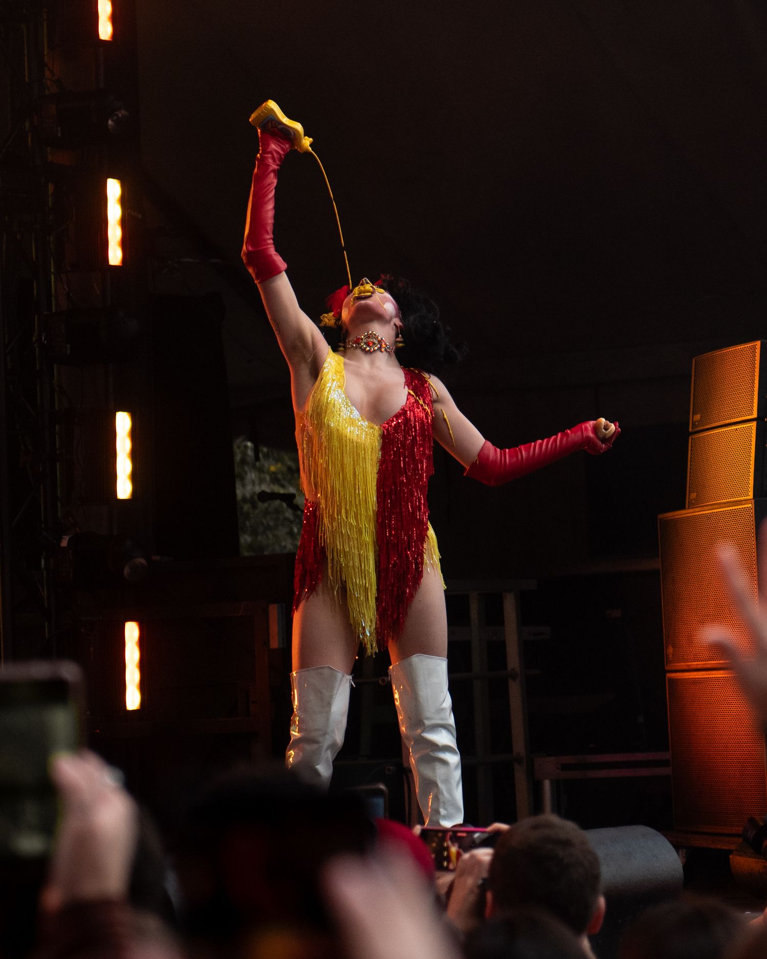 Theatrical performer in yellow and red costume on dark stage with dramatic lighting.