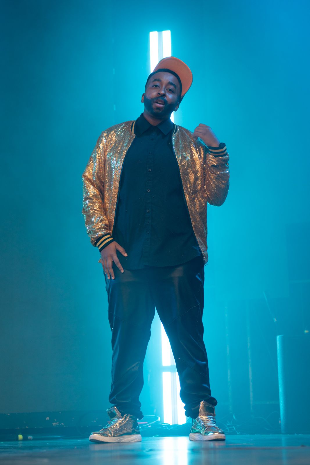 A figure in a gold jacket and black pants strikes dynamic poses against a blue-lit backdrop in a photo sequence.