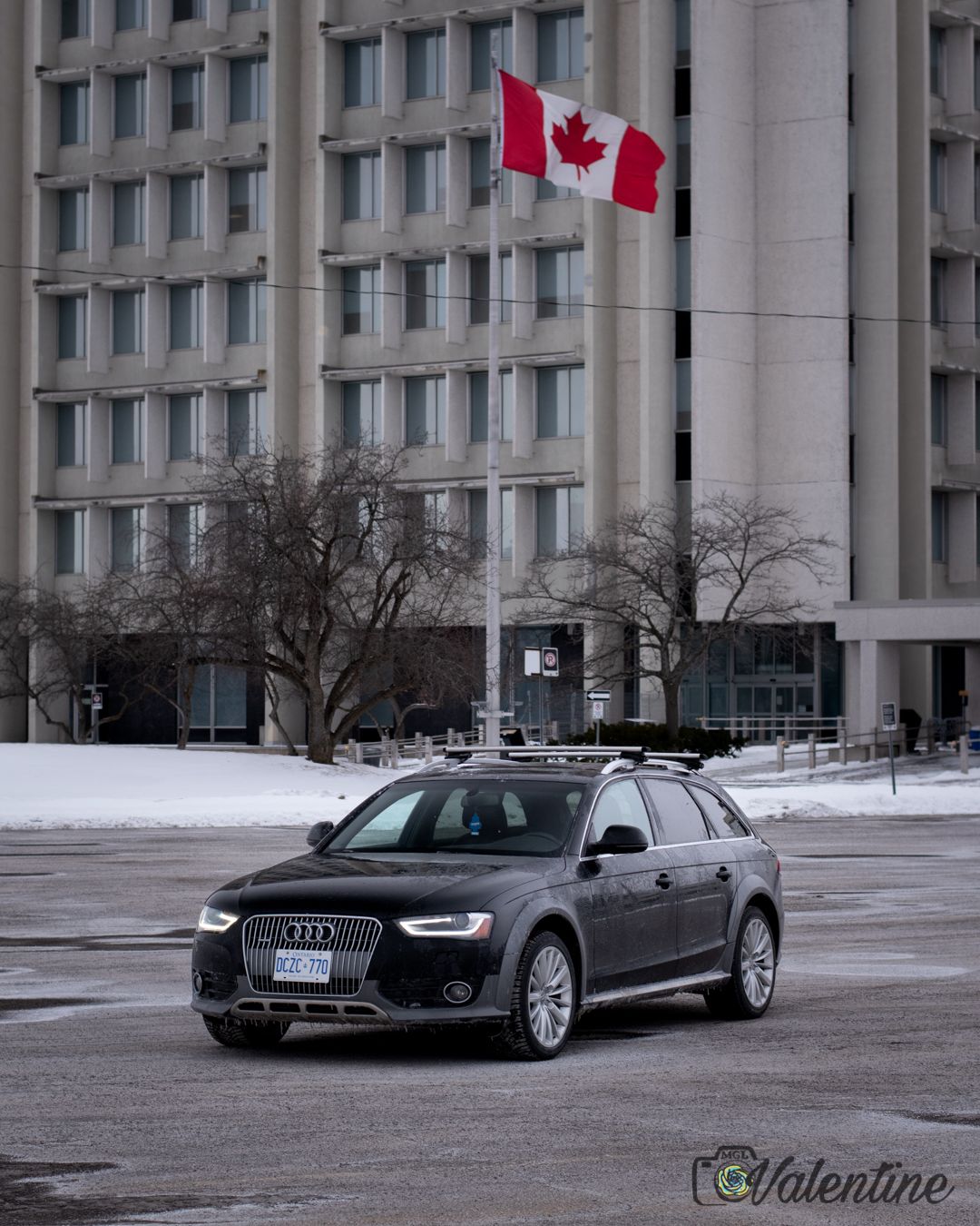 Luxury cars parked outside a modern building with Canadian flags.