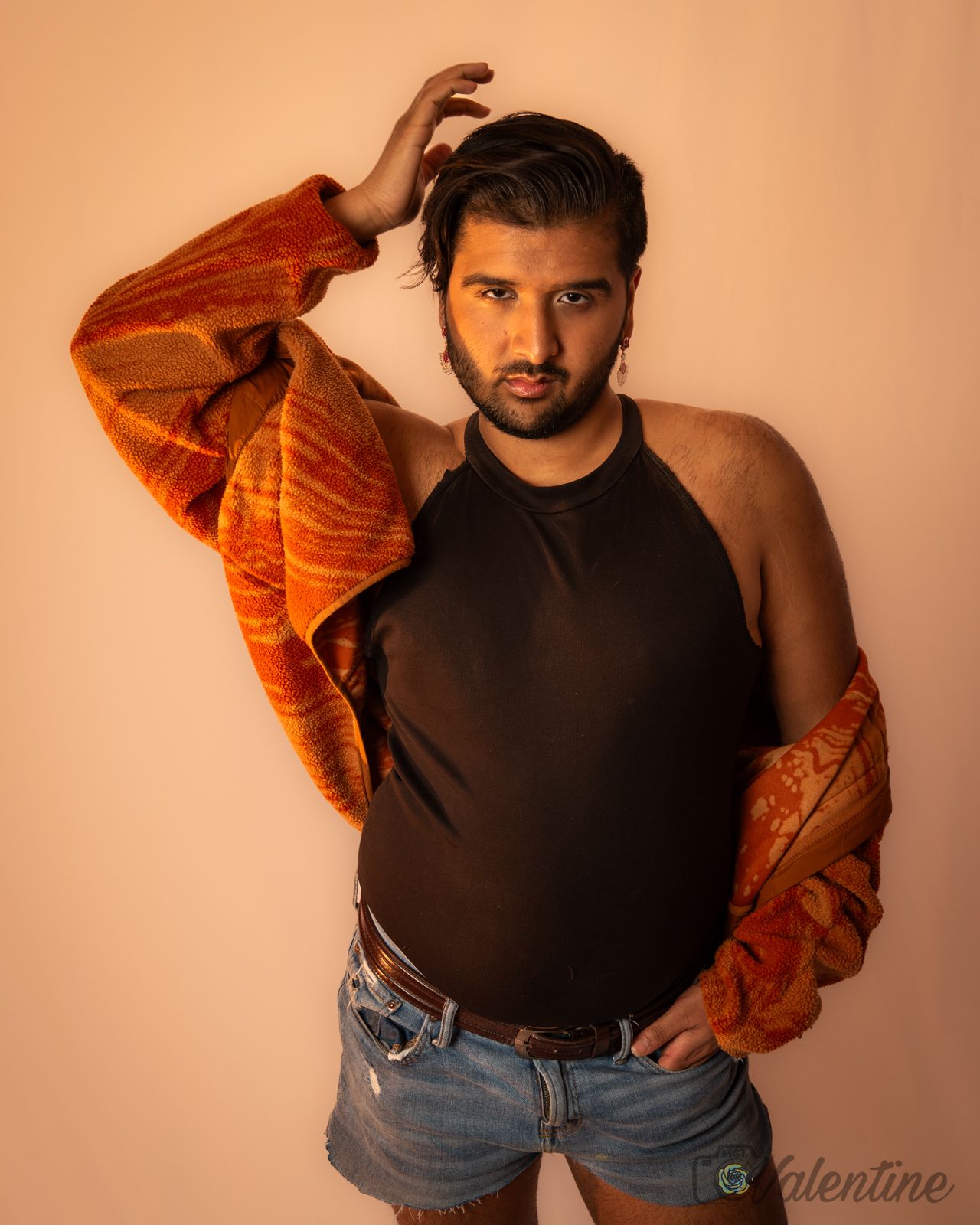A fashion photo series showing five poses in denim shorts and black top with an orange jacket against a peach background.
