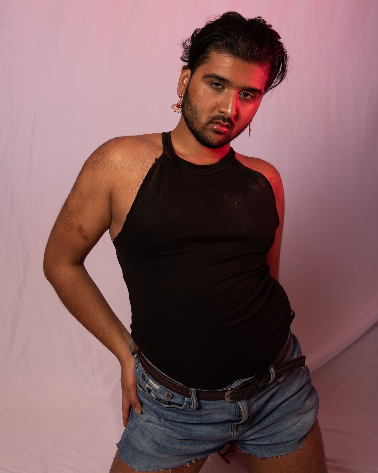 Fashion photography series with moody pink lighting showing person in black tank top and jeans.
