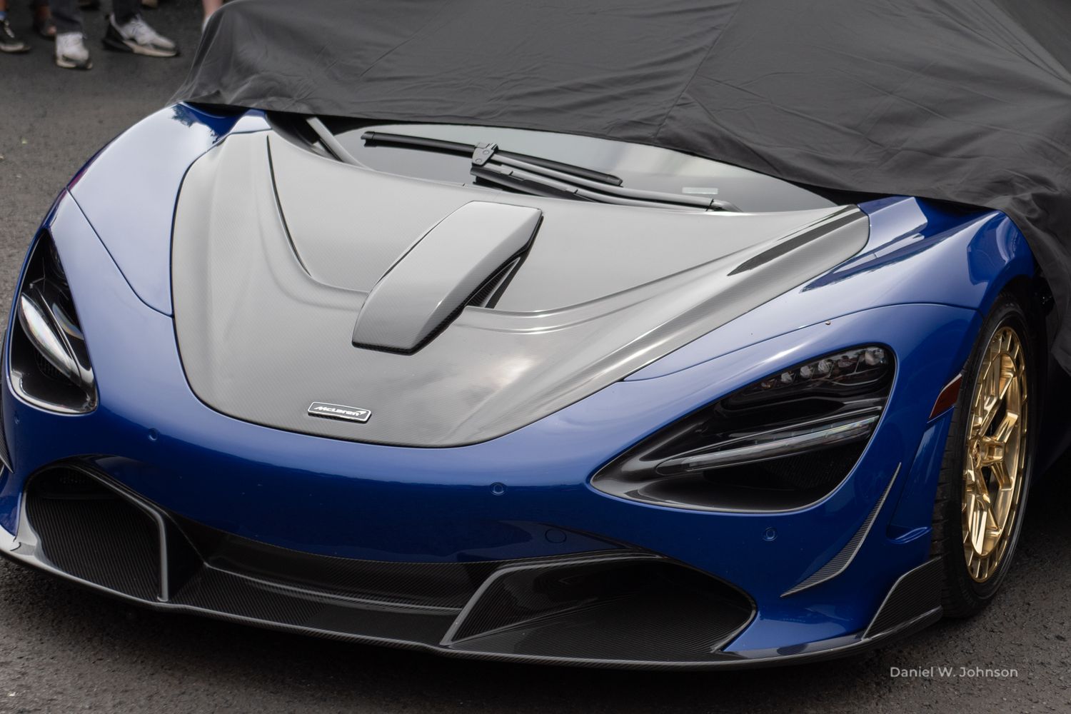 A sleek blue and silver McLaren P1 supercar showcases its aerodynamic design and distinctive butterfly doors.
