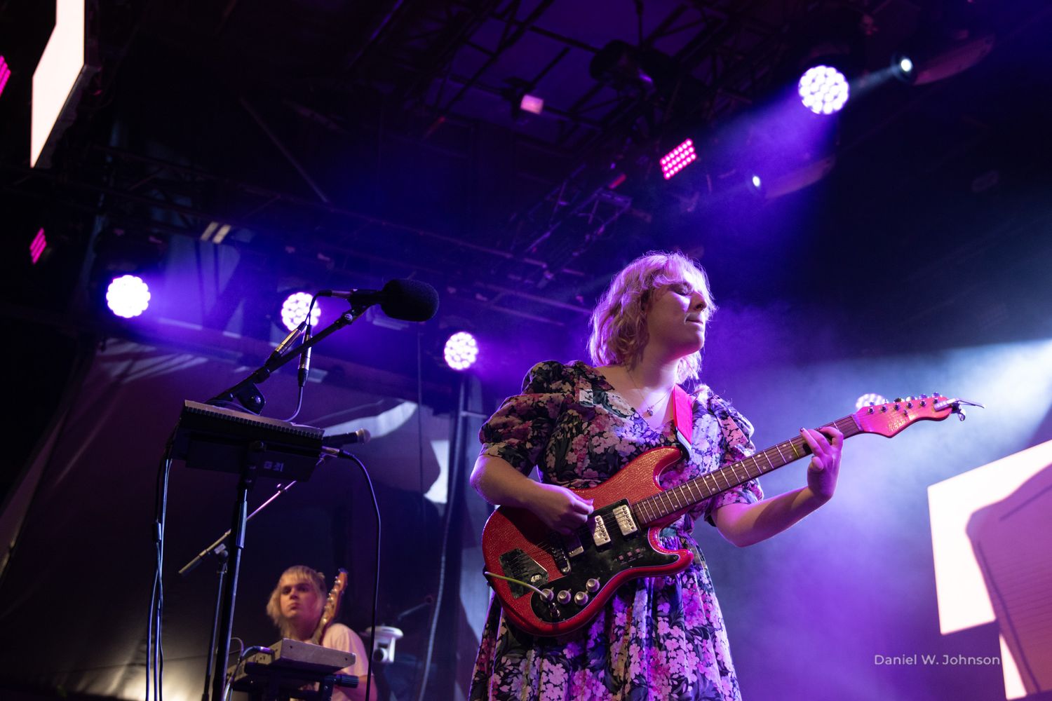 Rock concert with purple stage lighting and musicians playing instruments.
