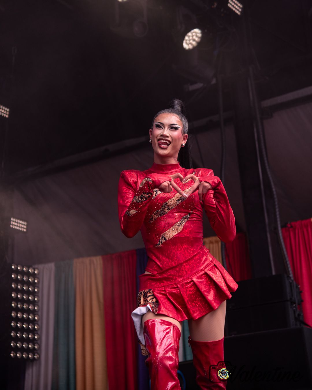 Performer in a red costume dancing energetically on a dark stage.