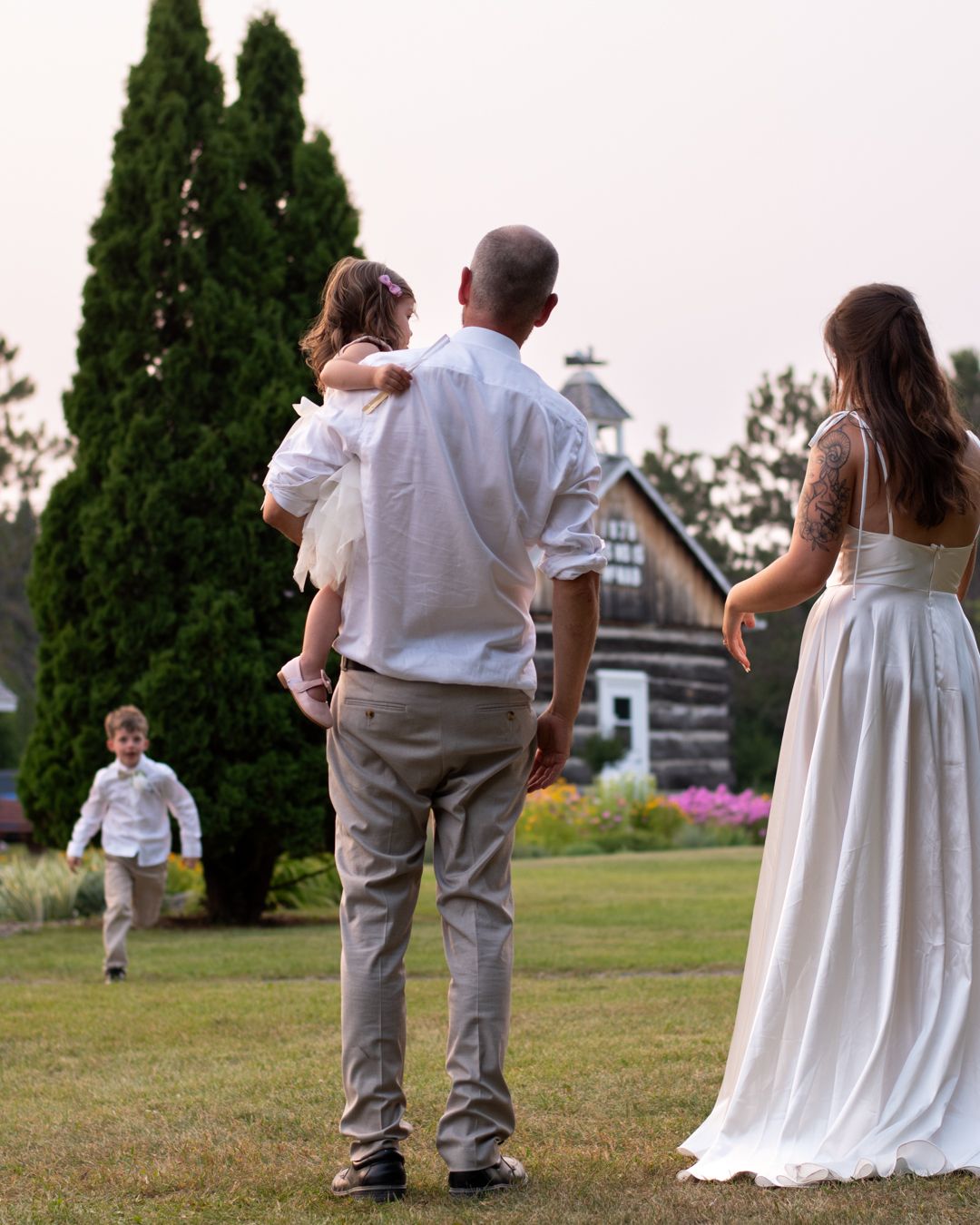 Wedding party walking across lawn with white dress and gray suits visible.