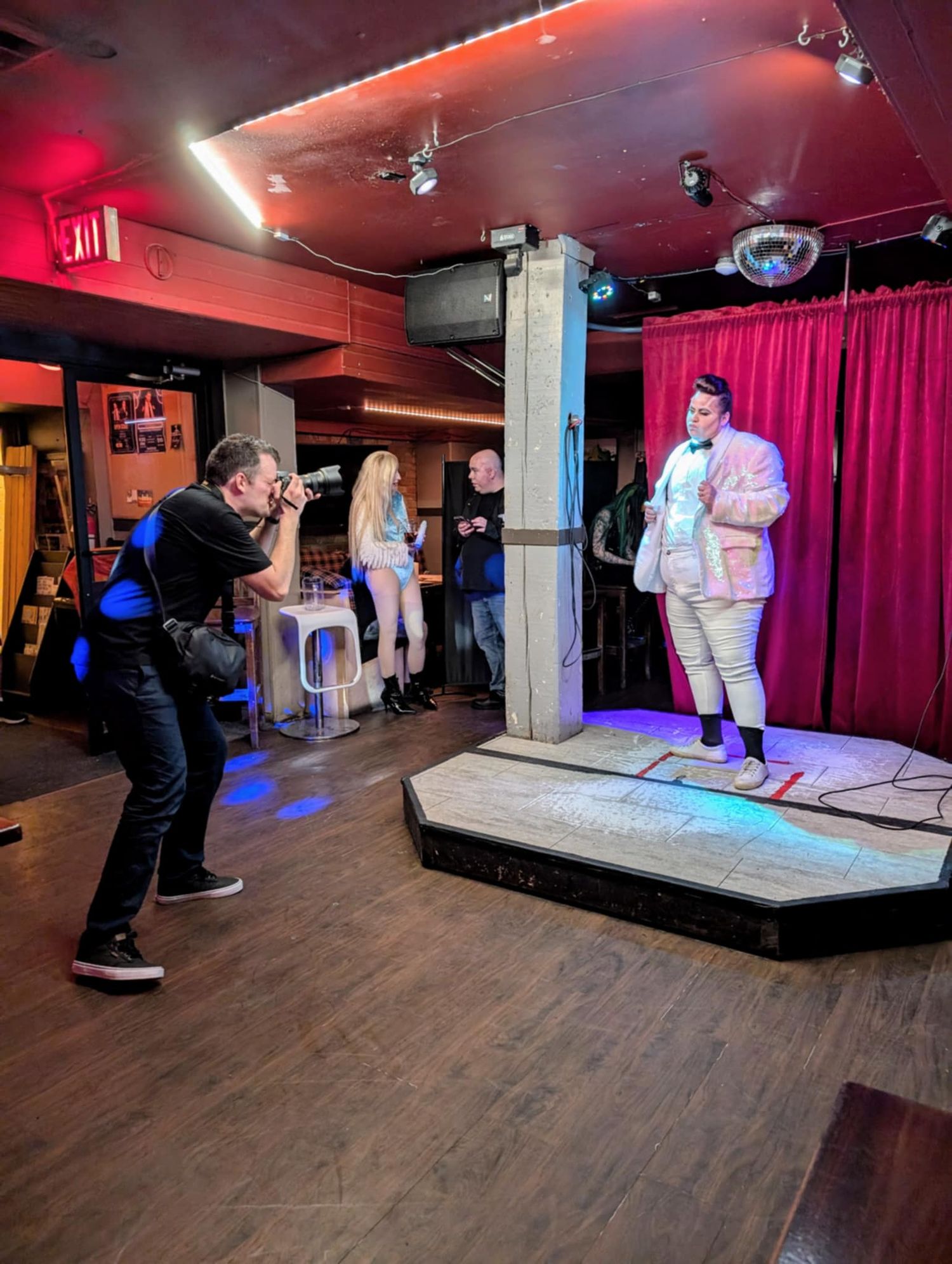A nightclub performance being photographed under red and blue stage lighting.