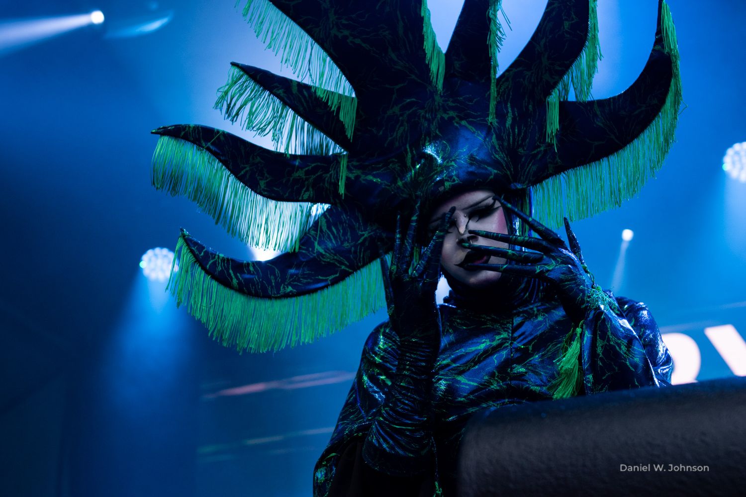 Dramatic blue stage lighting illuminates decorative props during a theatrical performance.