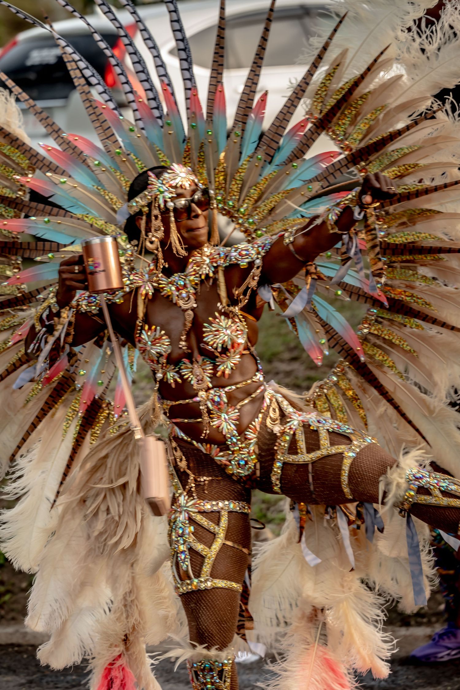 Vibrant carnival dancer in elaborate feathered gold costume with headdress performing at a festive parade celebration.