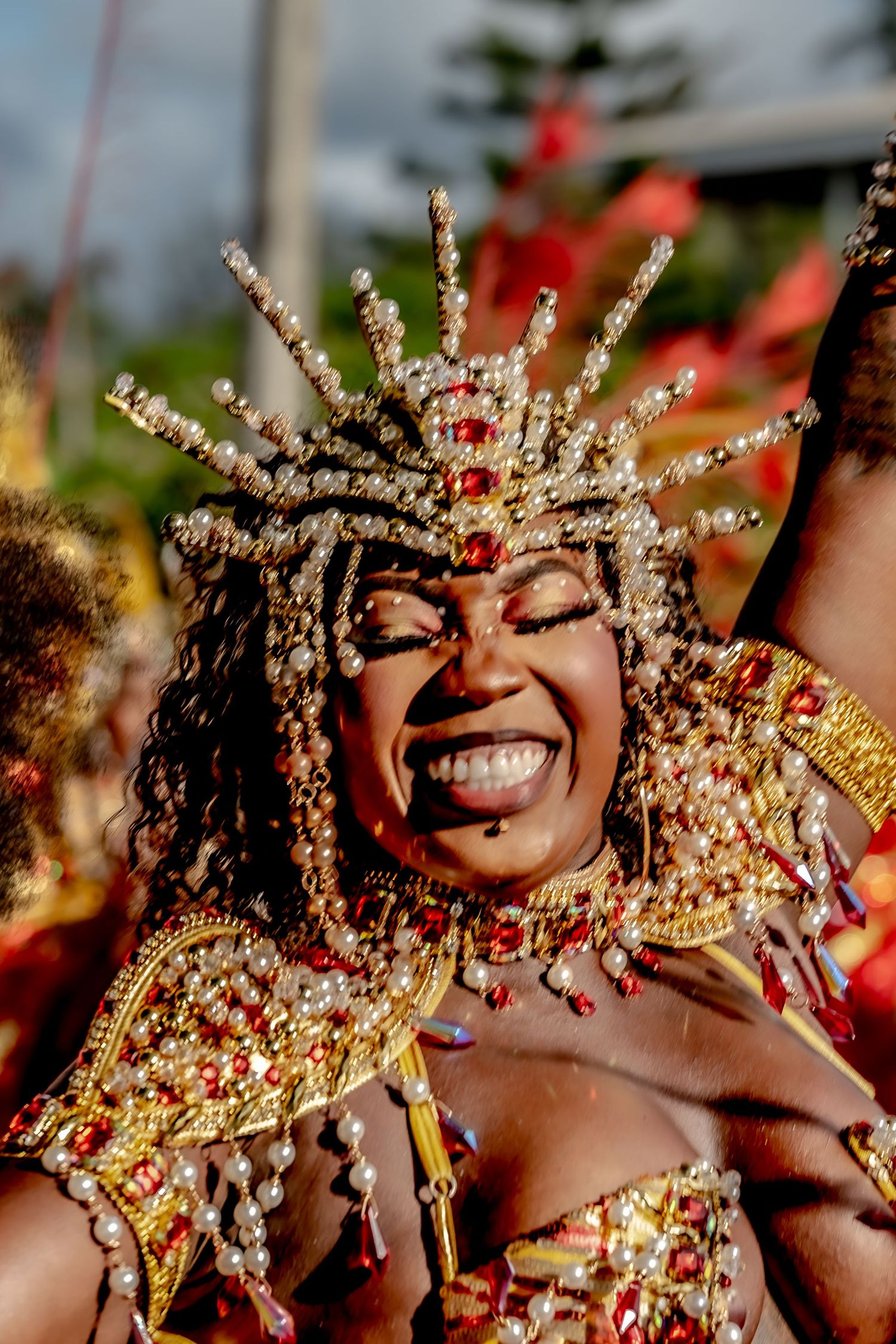 Joyful woman in elaborate gold and red beaded carnival costume and crown performing at festival.