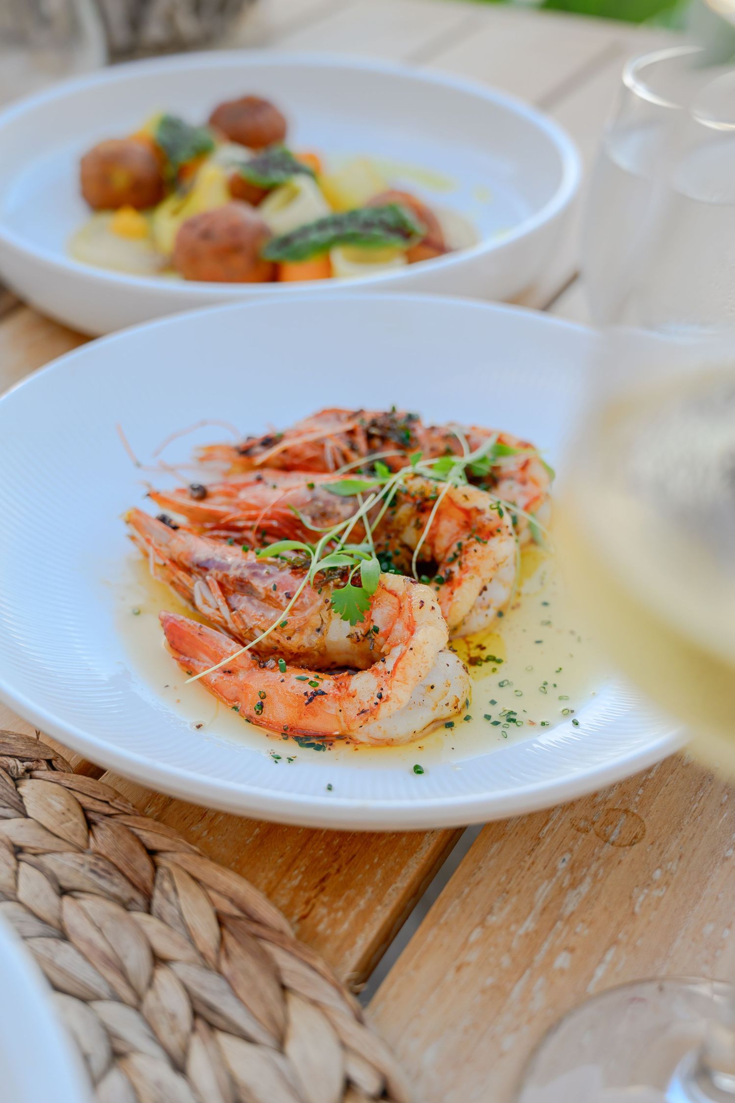 Grilled shrimp dish garnished with fresh herbs on a white plate.