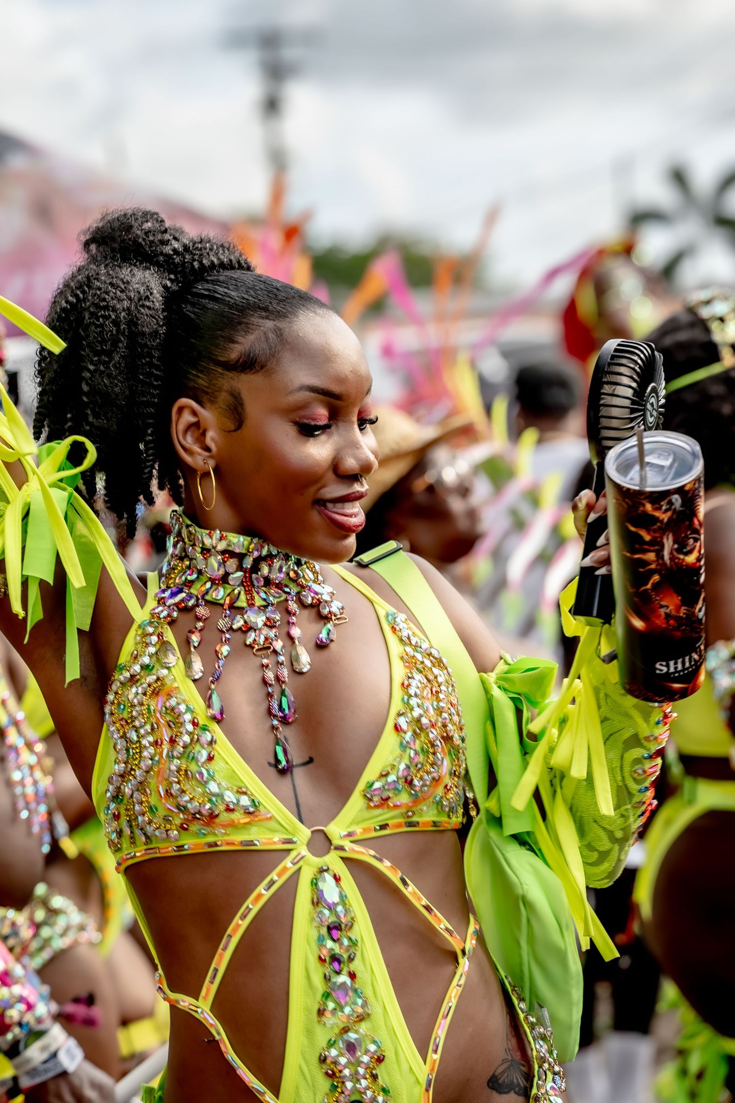 Woman in vibrant neon green carnival costume with jeweled bodice dancing at a tropical festival.