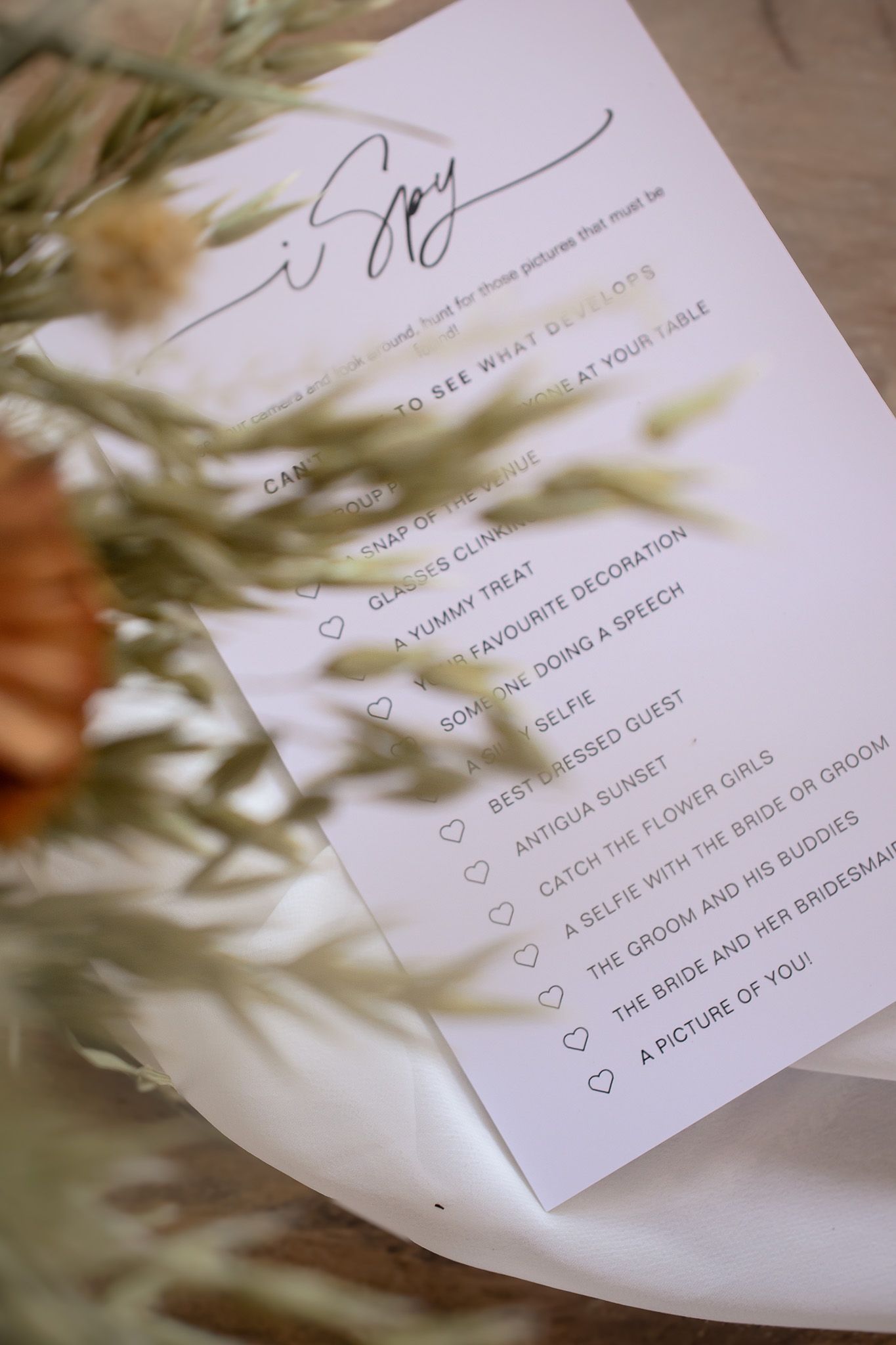 A wedding program checklist on white paper with blurred greenery shadows cast across it.