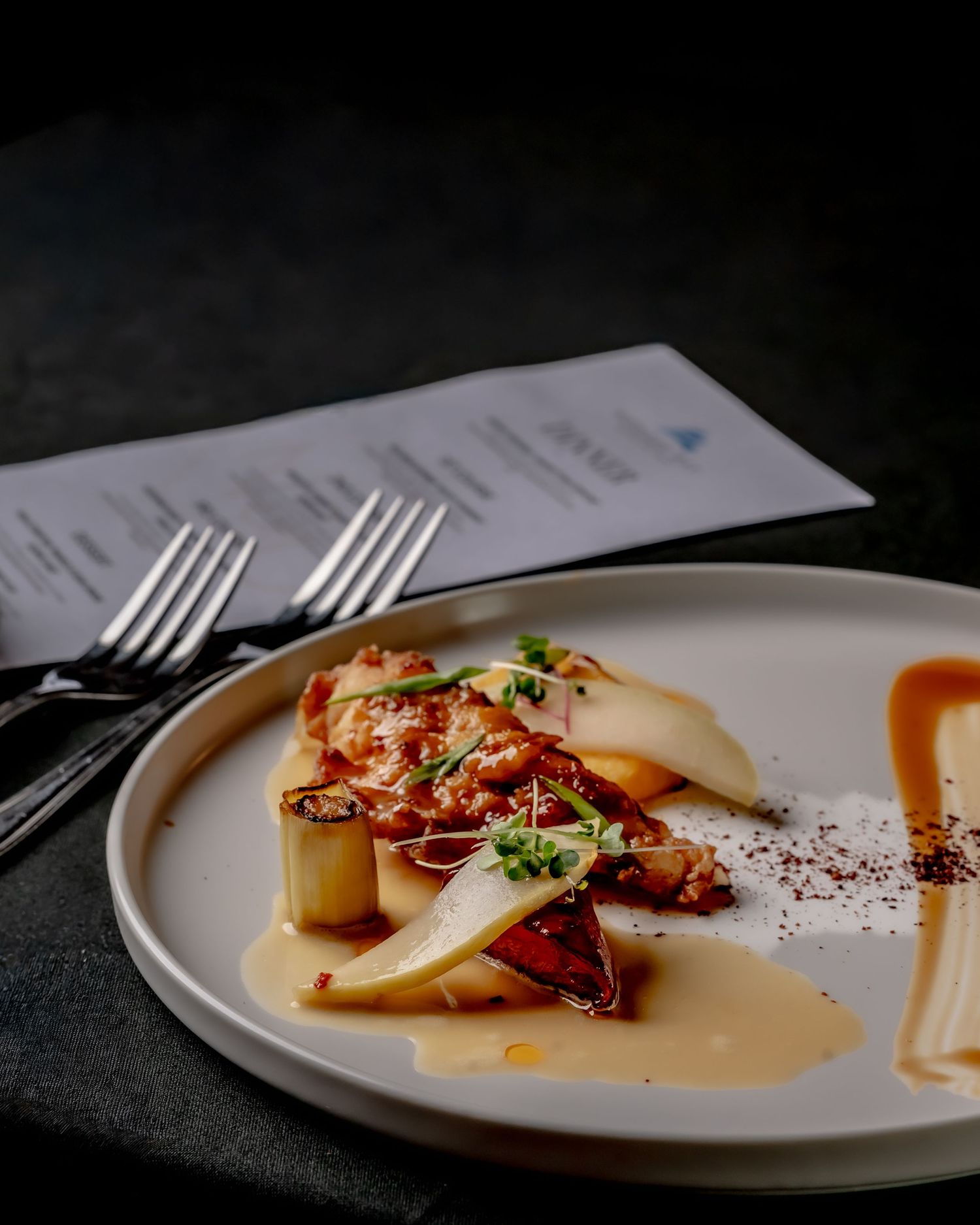 Elegant plated dish with glazed pears, caramelized protein, herb garnish, and golden sauce on a white ceramic plate.