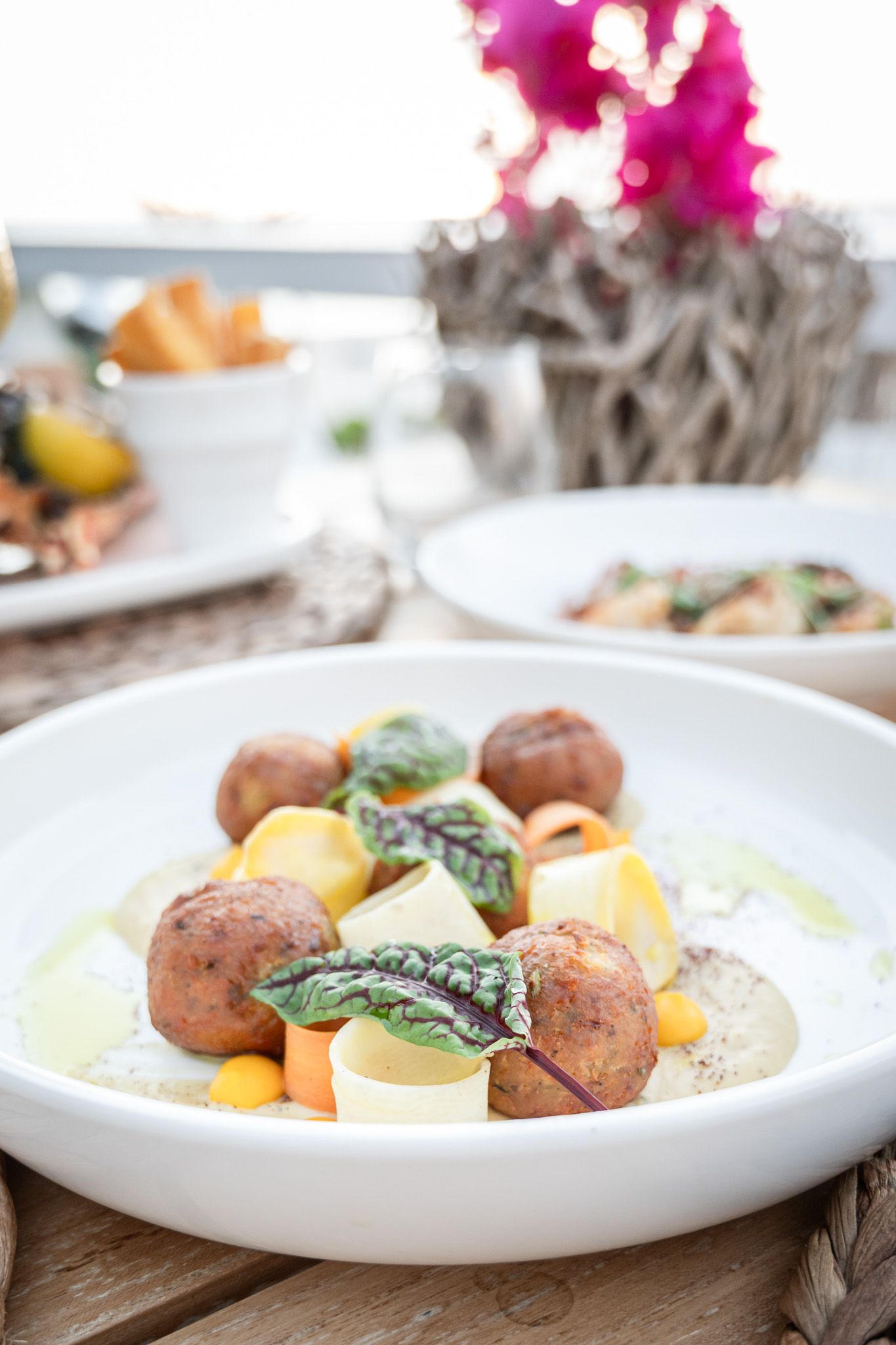 Roasted potatoes and vegetables served on a white plate with fresh herbs and garnishes.