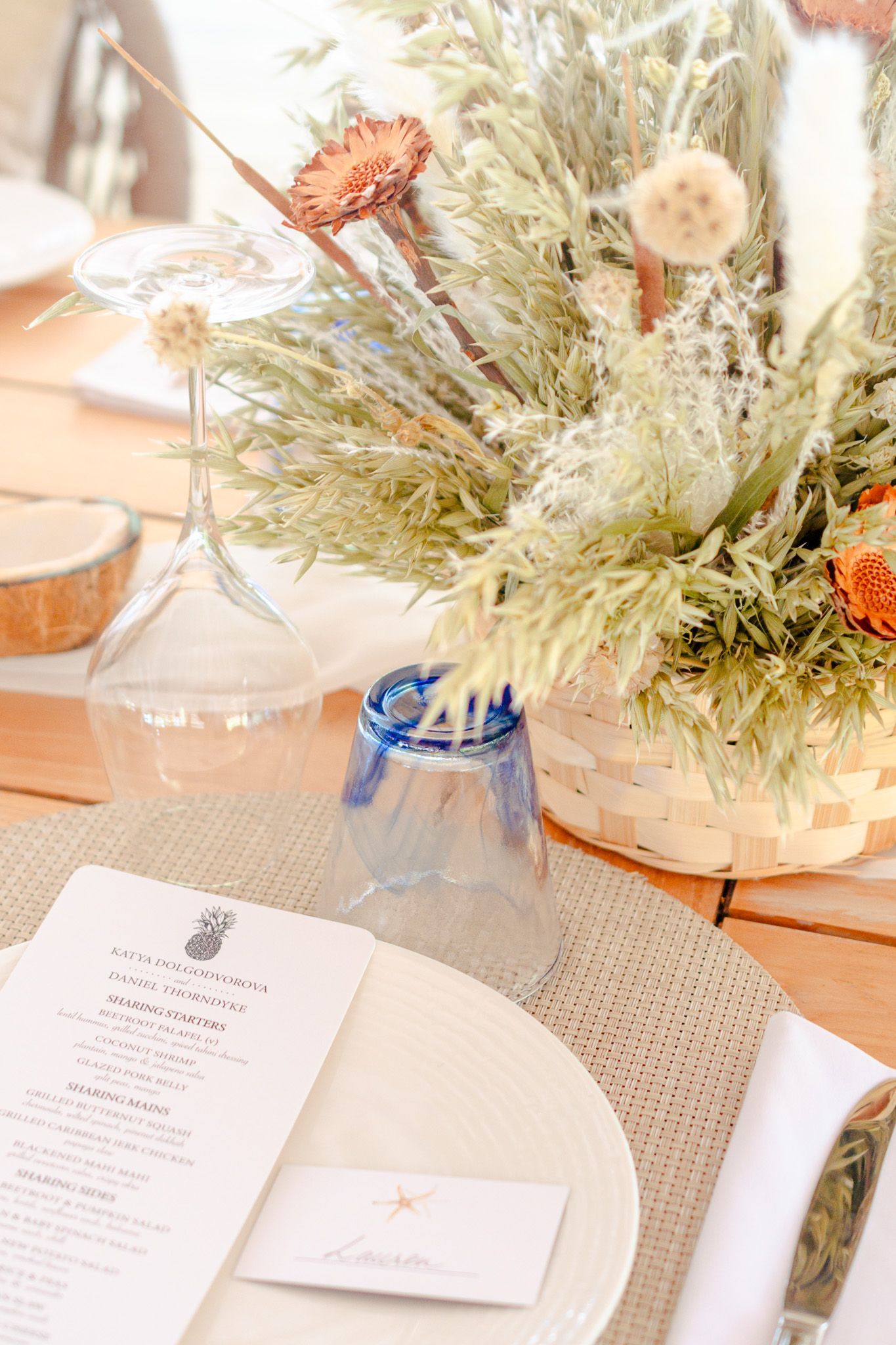 Elegant table setting with white plates, greenery centerpieces and menu cards at a formal dining event.