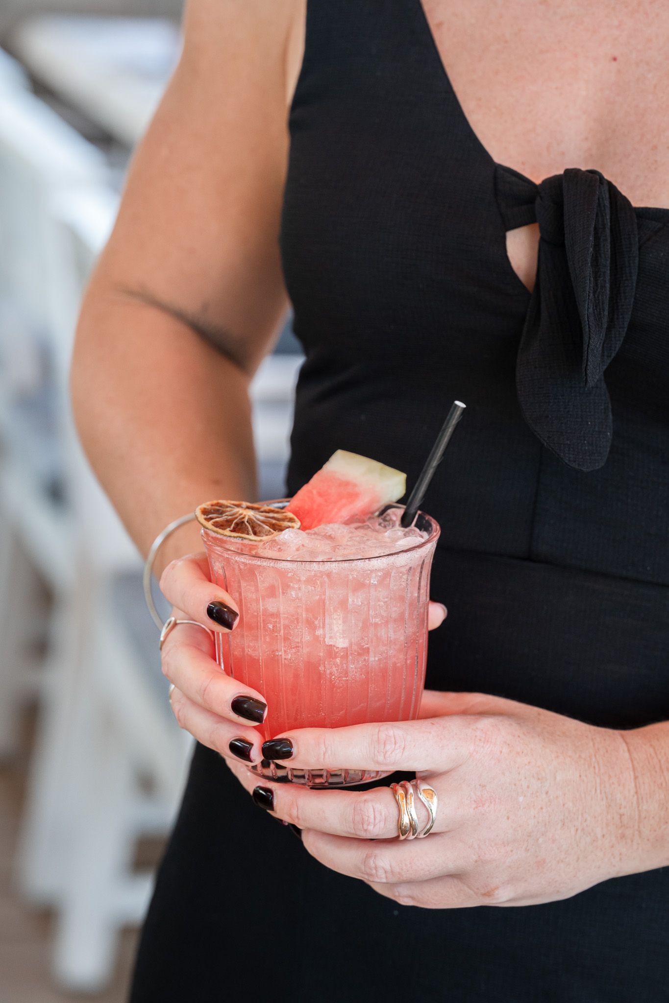 Hands holding pink cocktails garnished with citrus and served in crystal glasses.