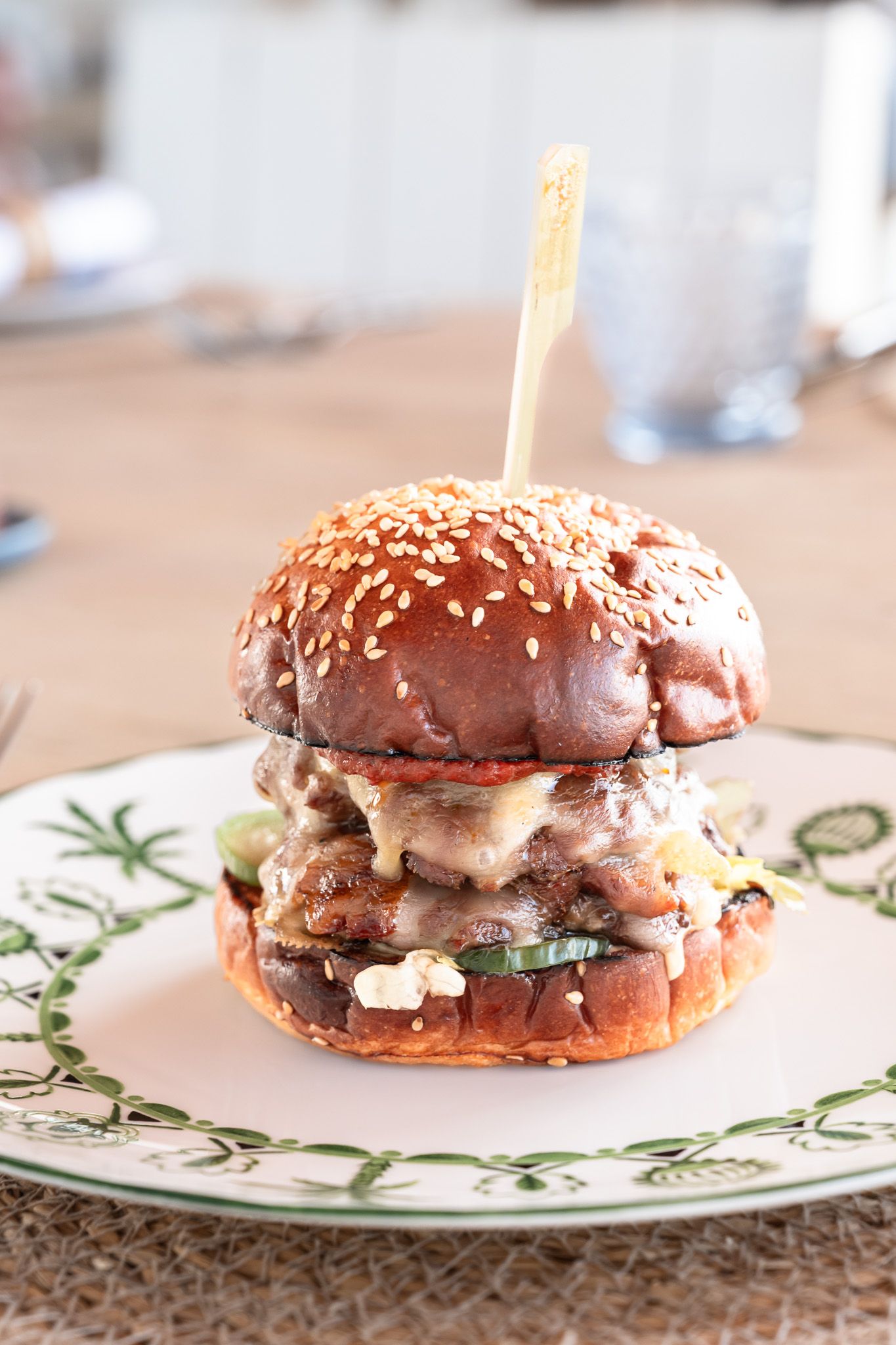 A sequence of gourmet burgers on decorative plates showcasing different toppings and sesame seed buns.
