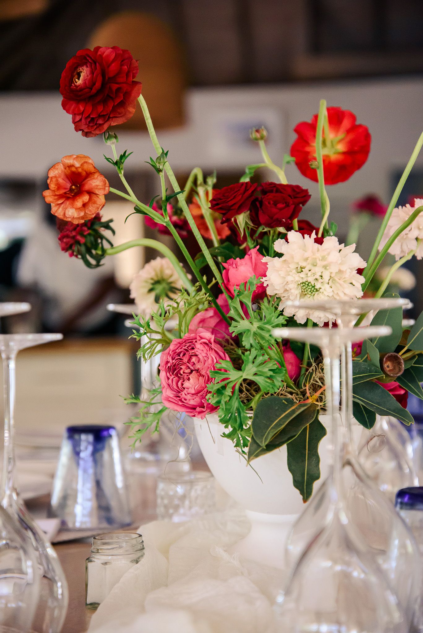 Red and pink flowers arranged in clear glass vases create an elegant table centerpiece display.