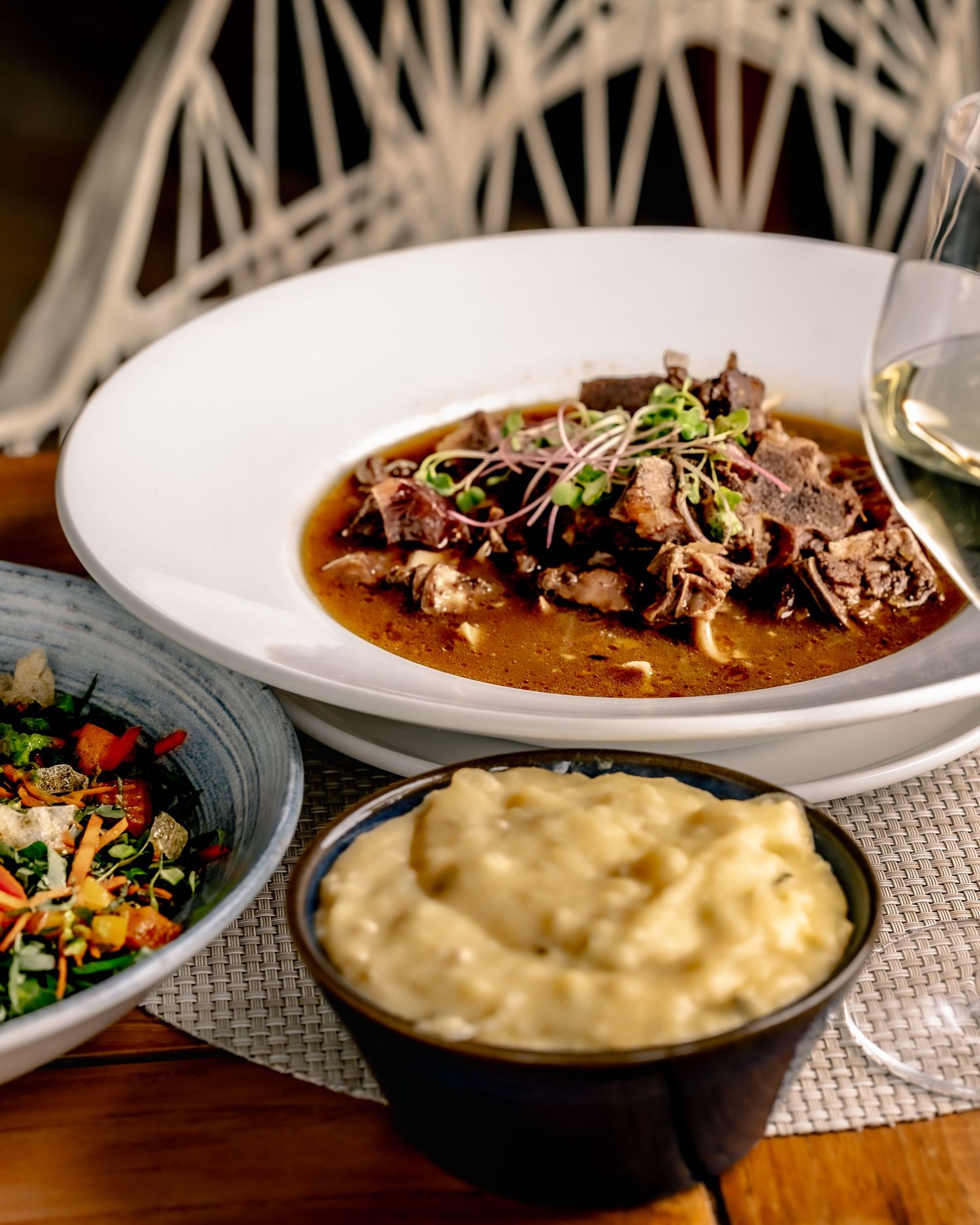 Braised beef in rich gravy served with creamy mashed potatoes and a fresh vegetable salad on a restaurant table.