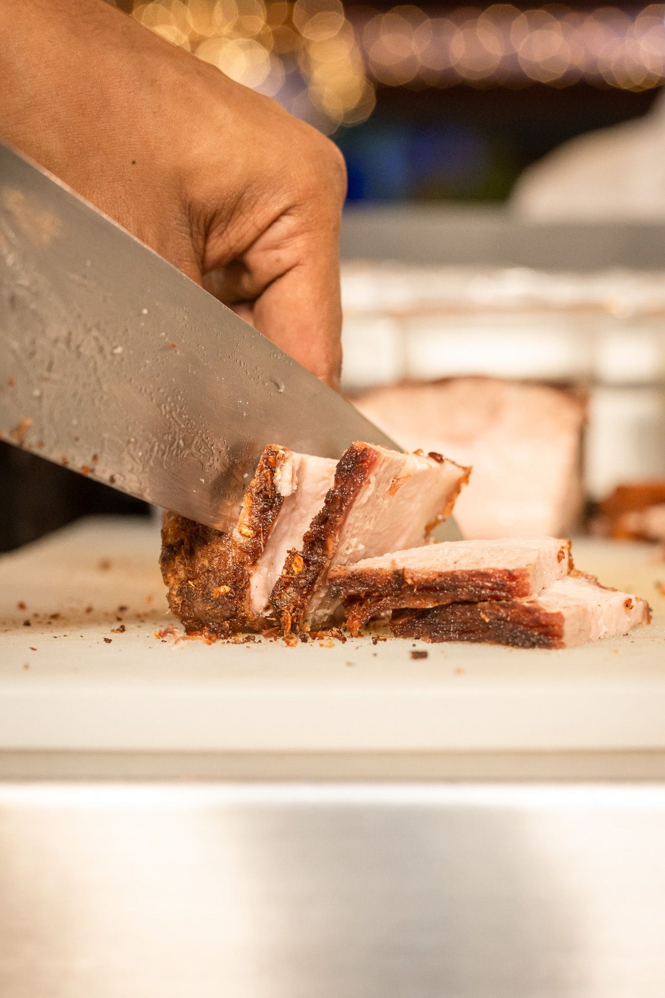 Close-up sequence of hands slicing chocolate cake on a white surface with a sharp knife.