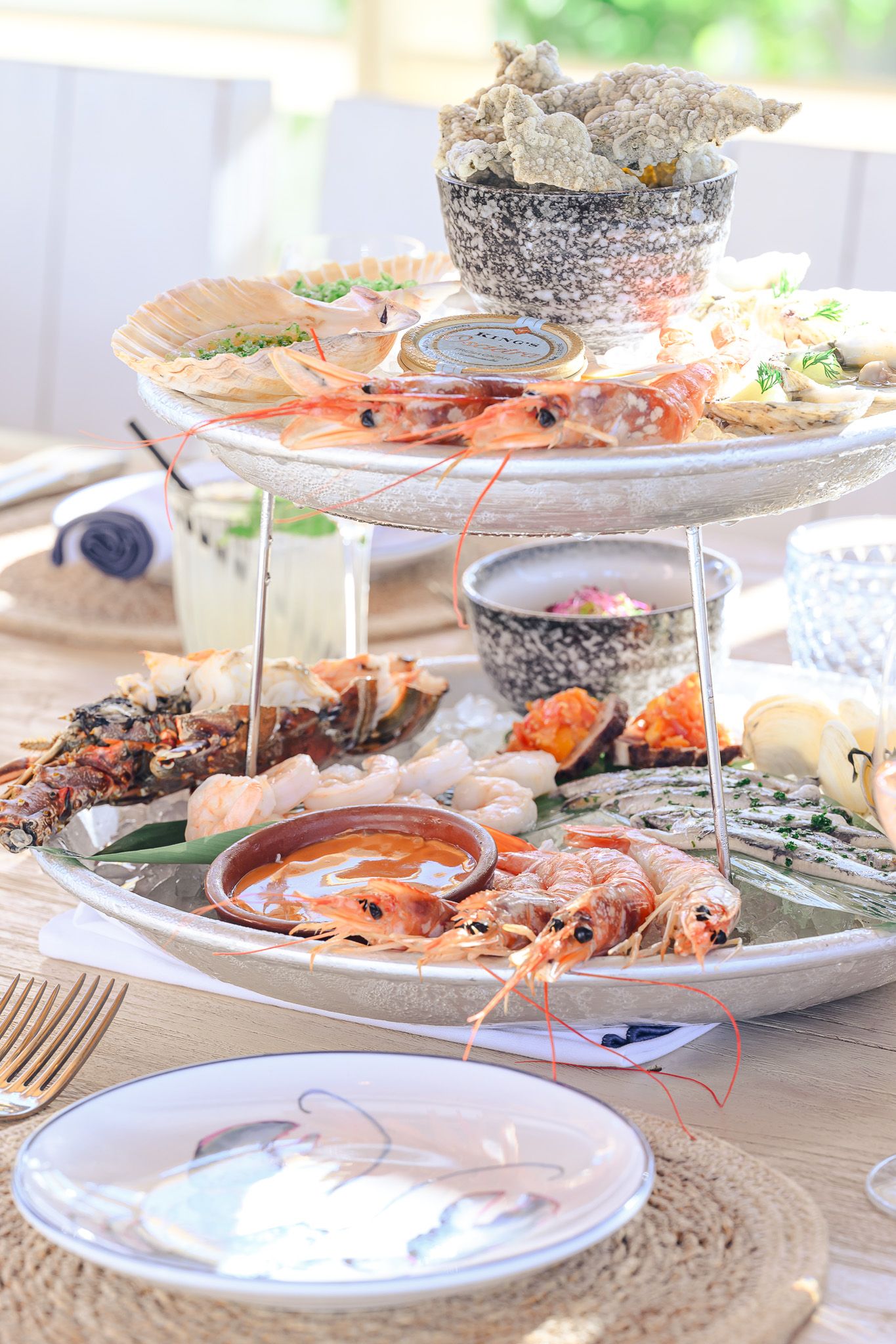 Elegant seafood platter display with fresh lobster and shellfish arranged on tiered white serving stands at an upscale event.