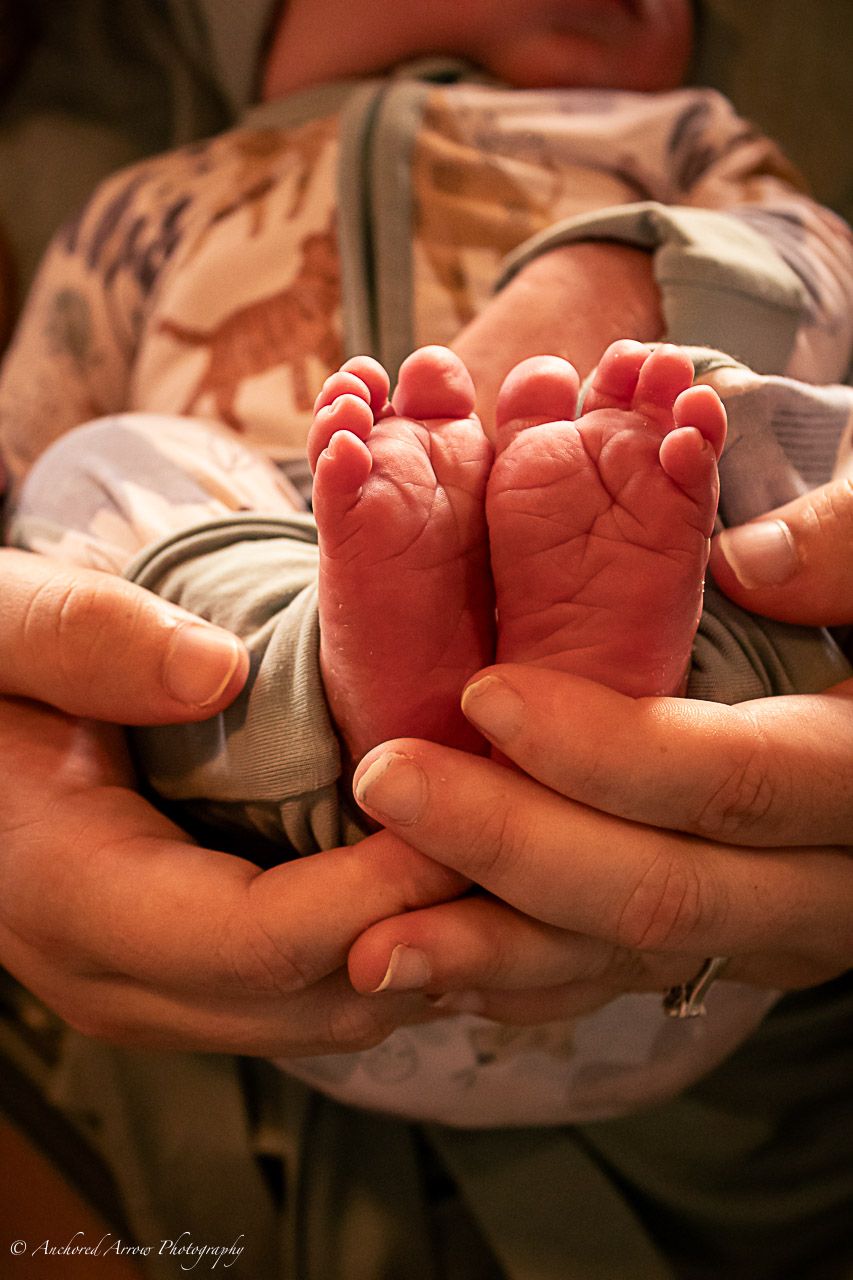 Close-up of newborn baby tiny feet cradled gently in loving parent hands.