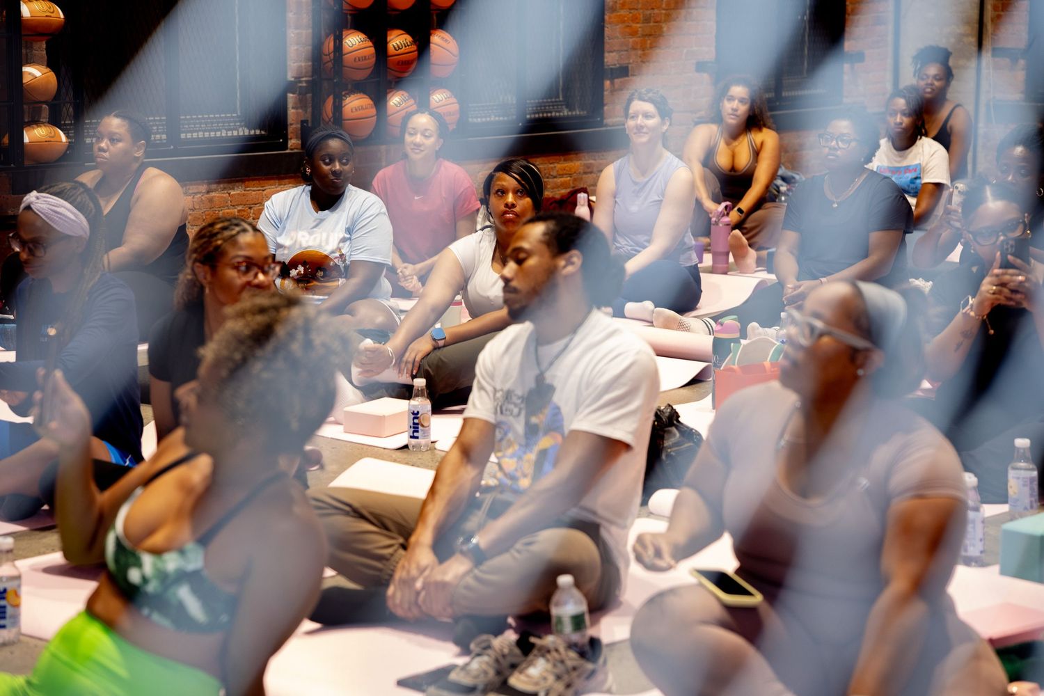 Diverse group of people sitting at tables in a meeting room, engaged in discussion during a workshop or seminar.