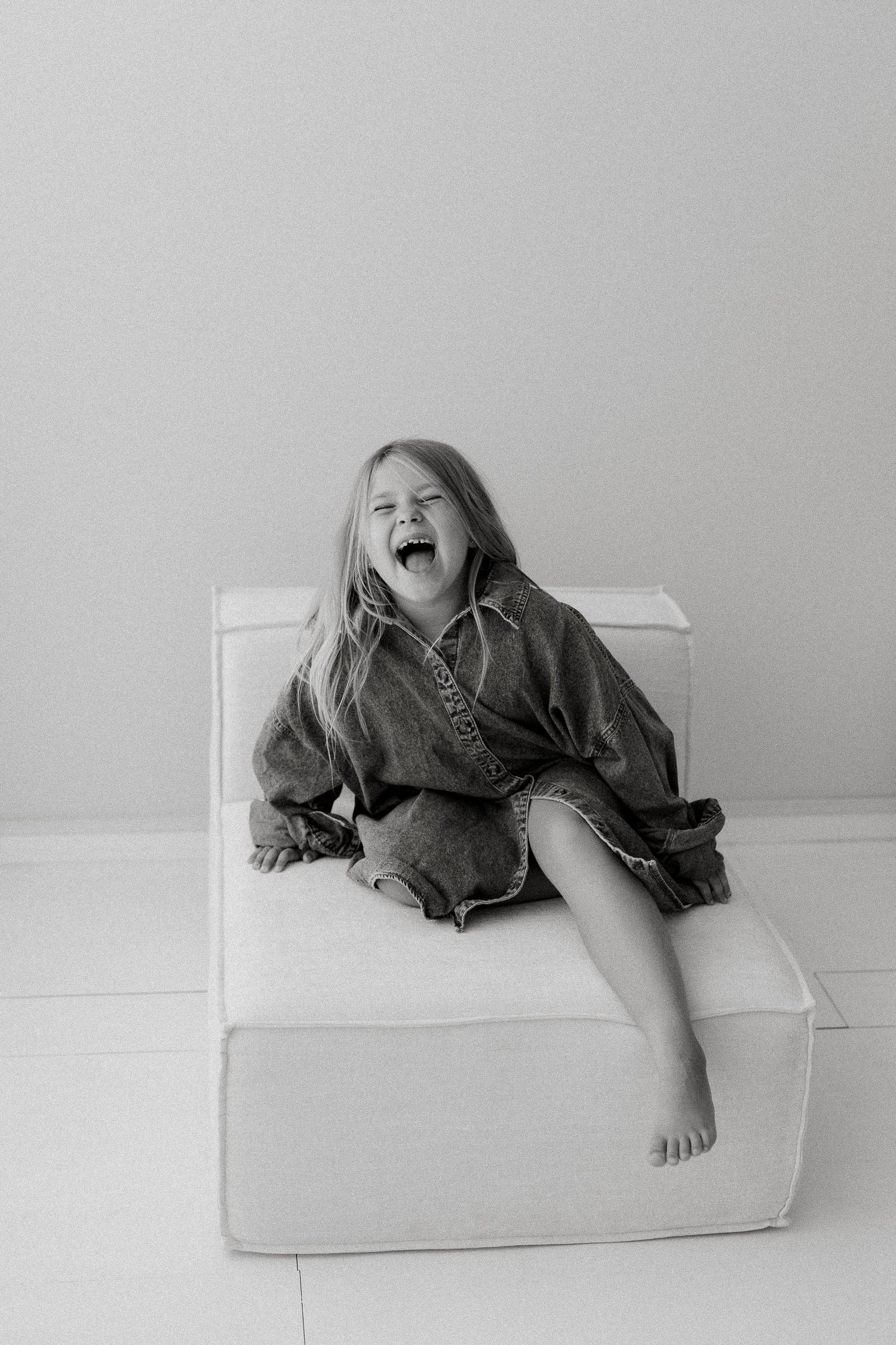 Black and white image of a joyful young girl having her shoot at Kirsty Beaumont Photography's Peregian Beach Studio