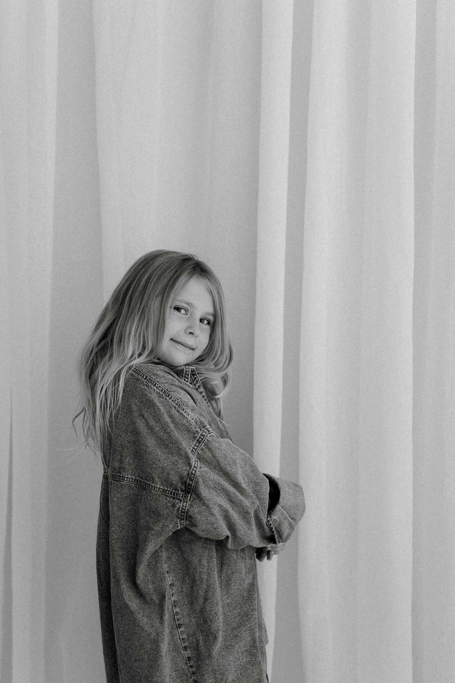 Personality Studio Black and white portrait of a smiling young girl in an oversized denim jacket at Kirsty Beaumont Photography Studio