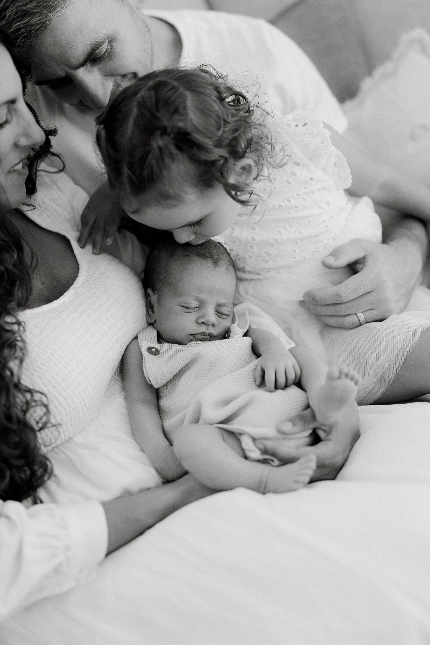 Sibling cuddling newborn baby during family photography session on Sunshine Coast