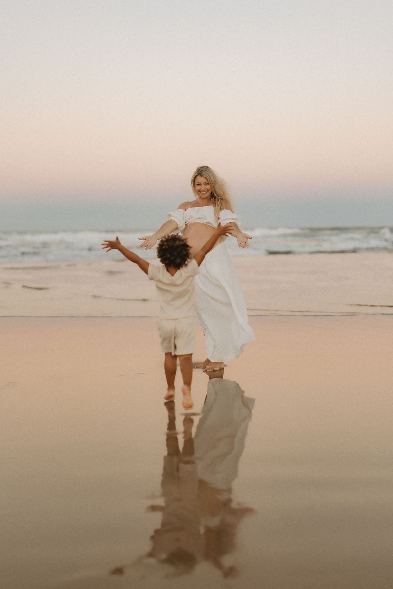 Pregnant mother standing on Sunshine Coast beach during sunset maternity photography session