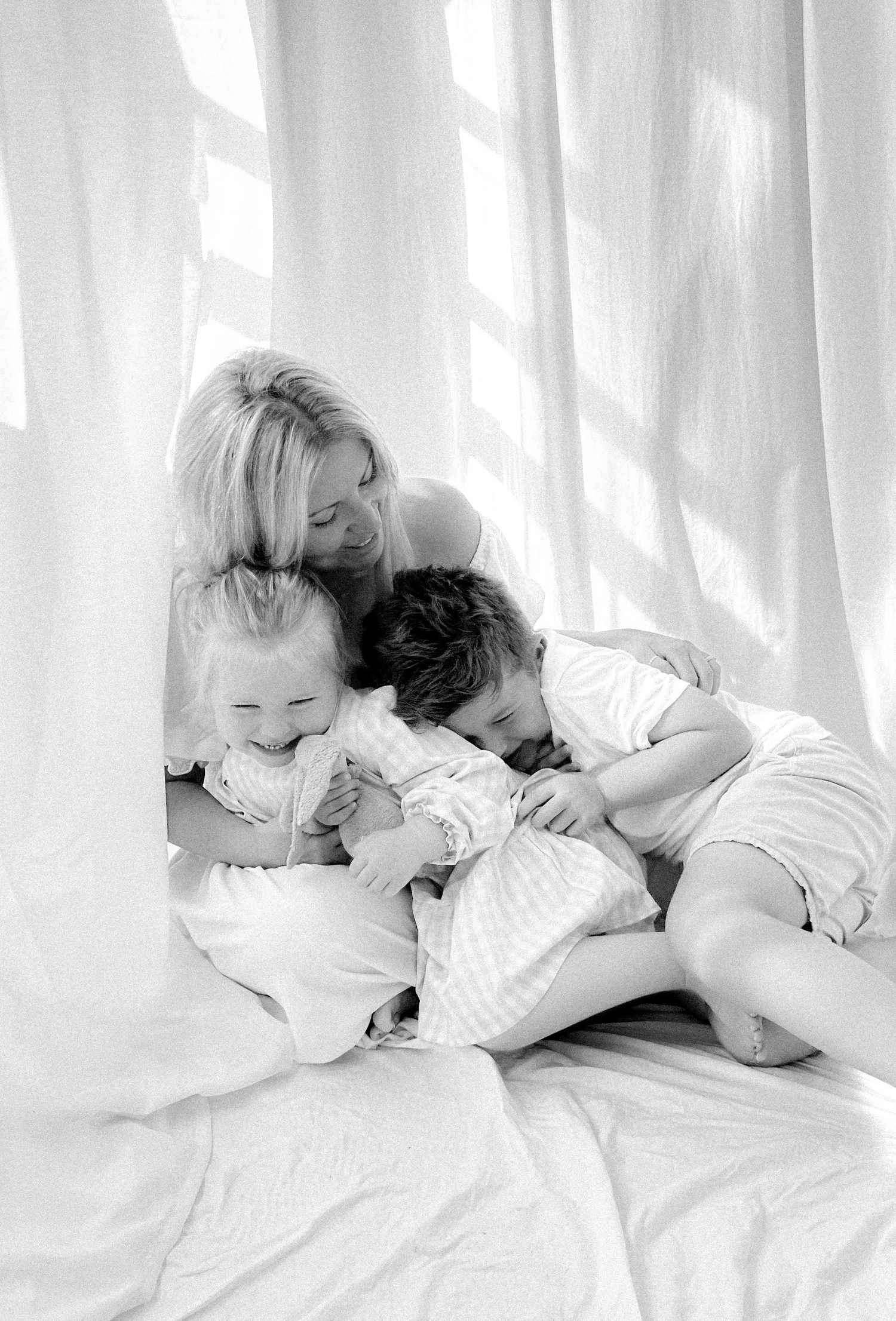 Mum cuddling her newborn baby in natural light photography studio in Peregian Beach