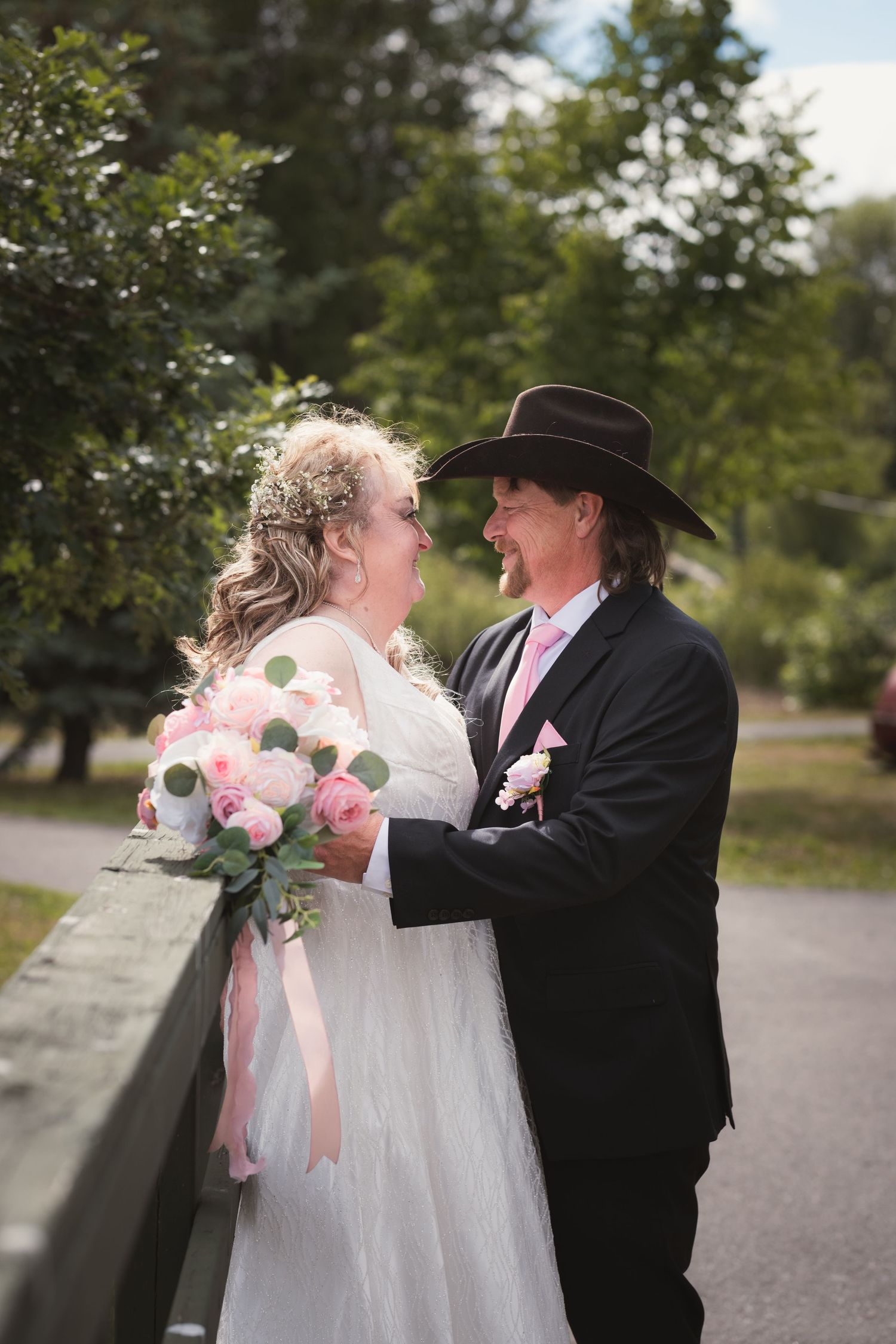 Bride and groom sharing a romantic moment on a bridge outdoors.