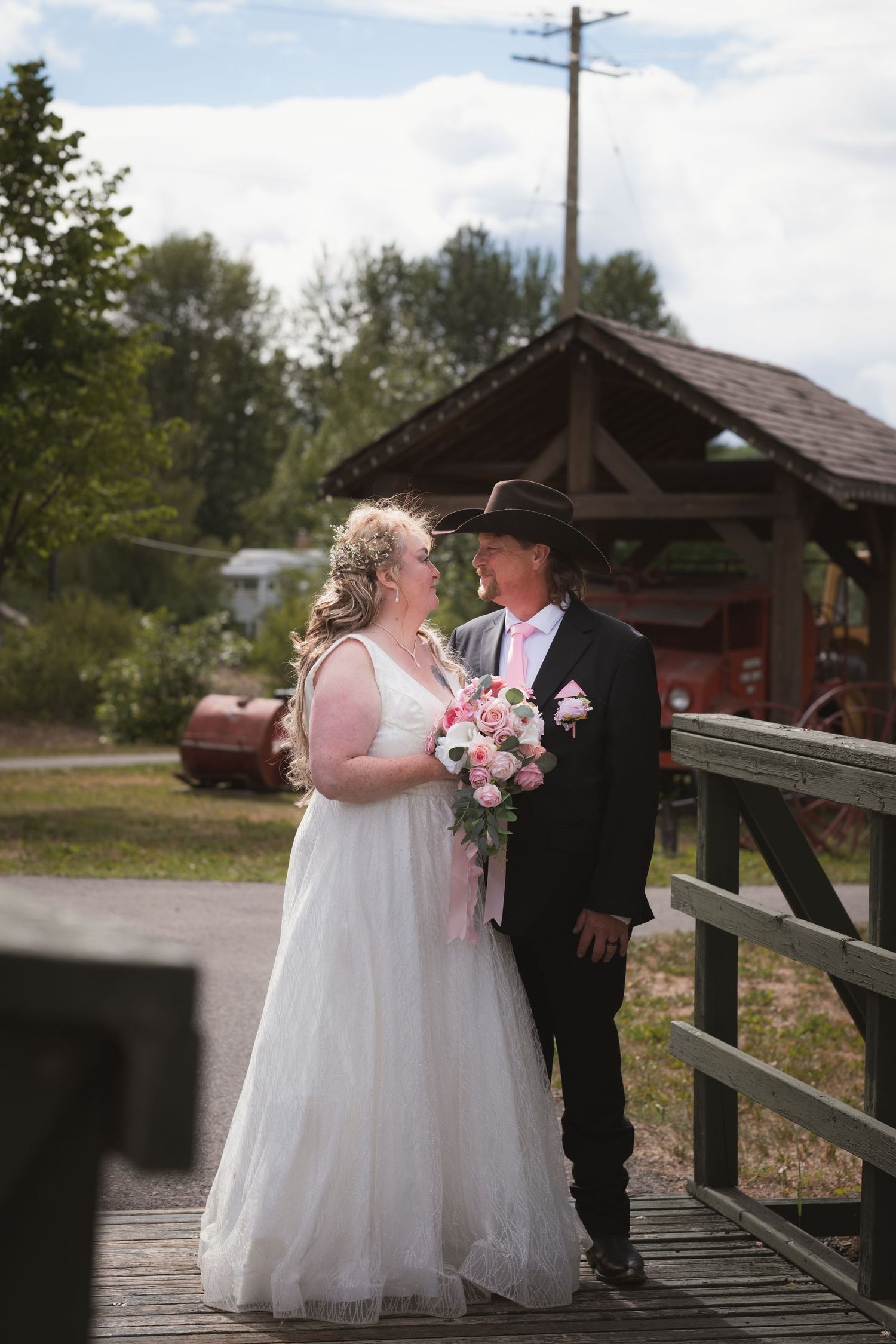 Bride and groom standing on wooden bridge gazing at each other.