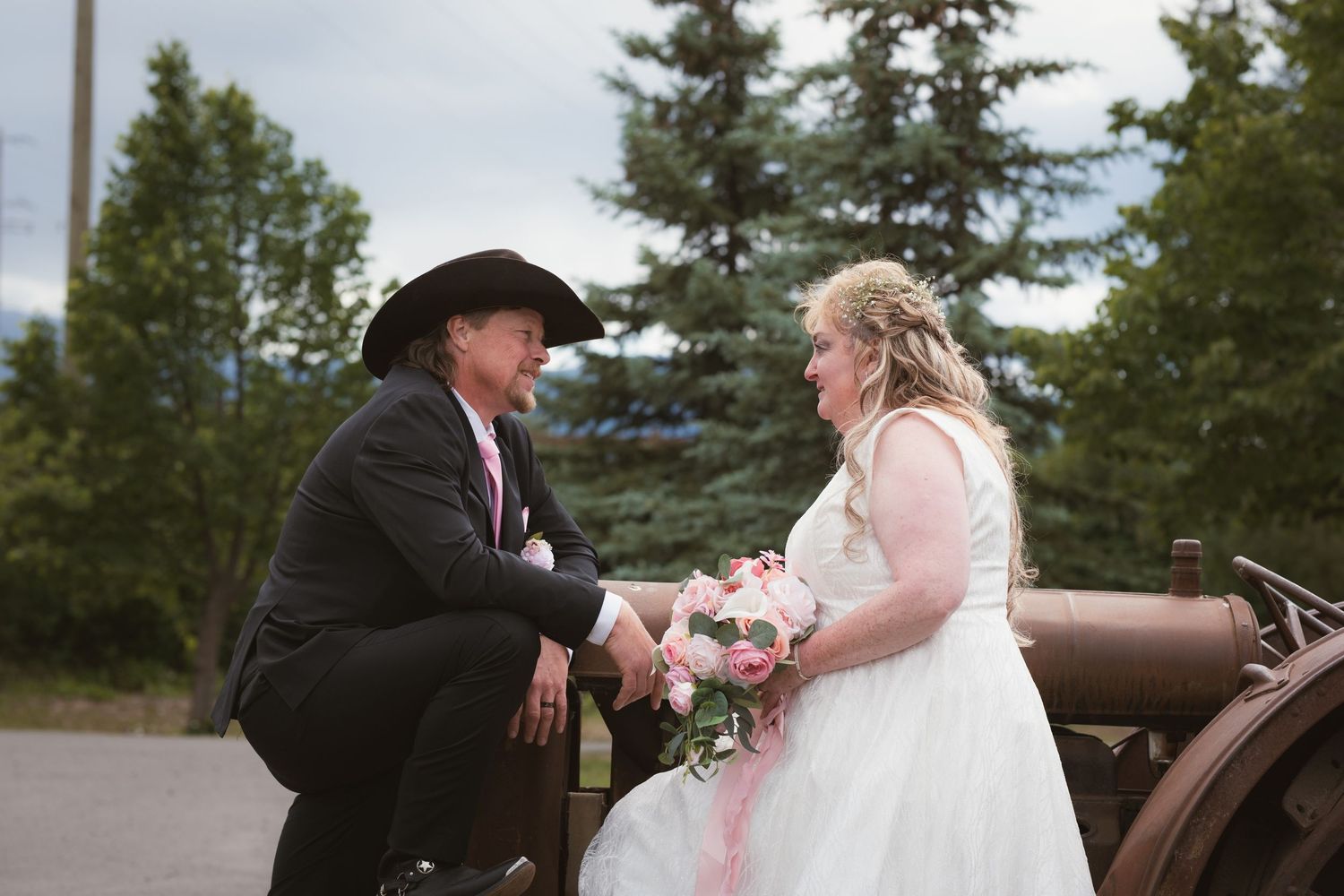Bride and groom sharing a moment seated on vintage cannon outdoors.