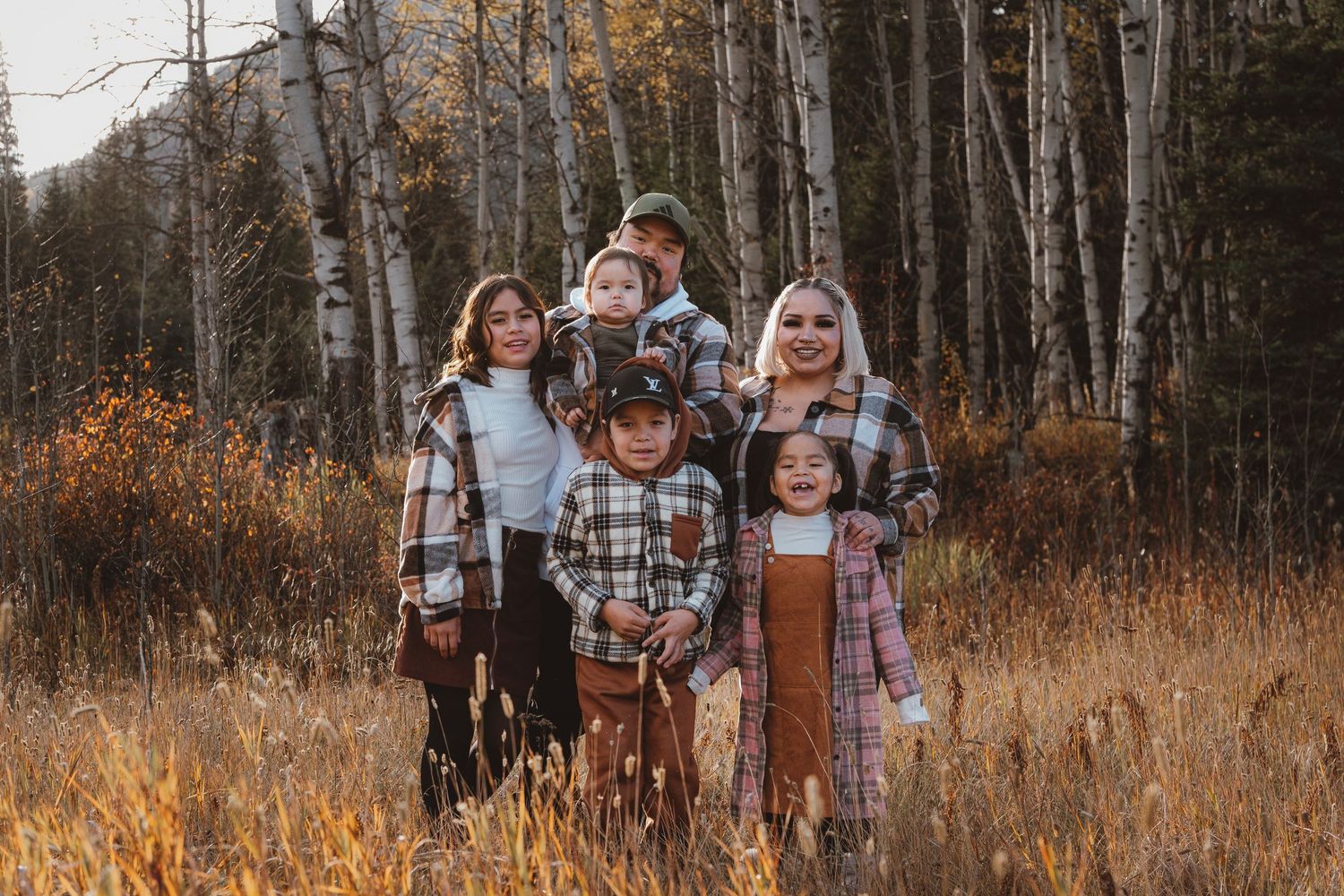 Large family group posing together in a golden autumn aspen forest meadow.