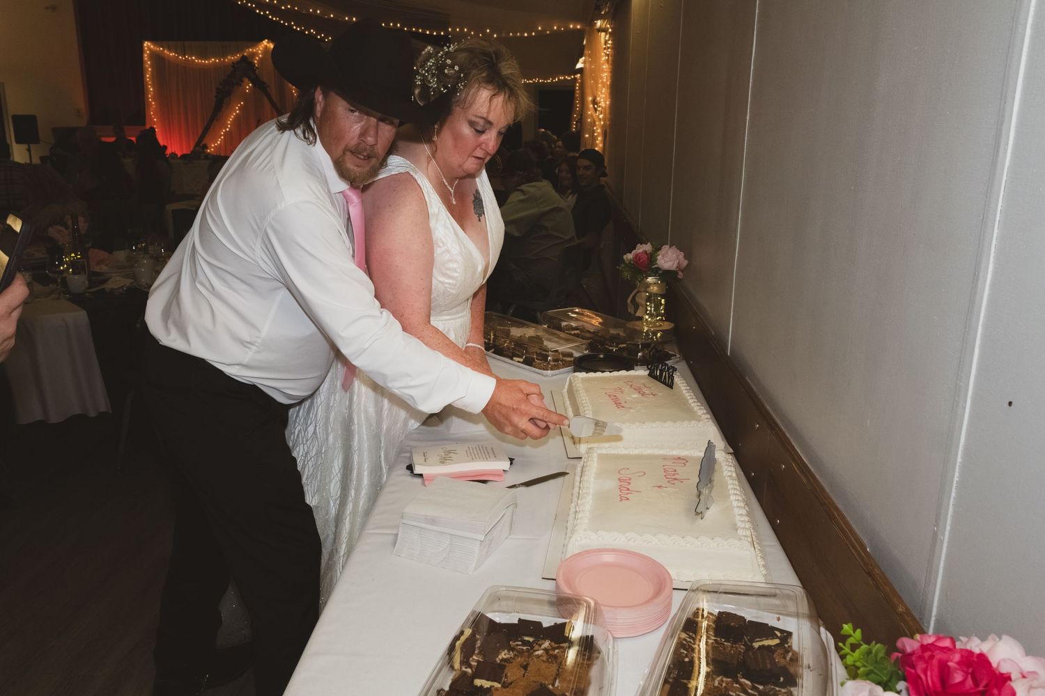 Bride and groom cut their wedding cake together at a decorated reception table.