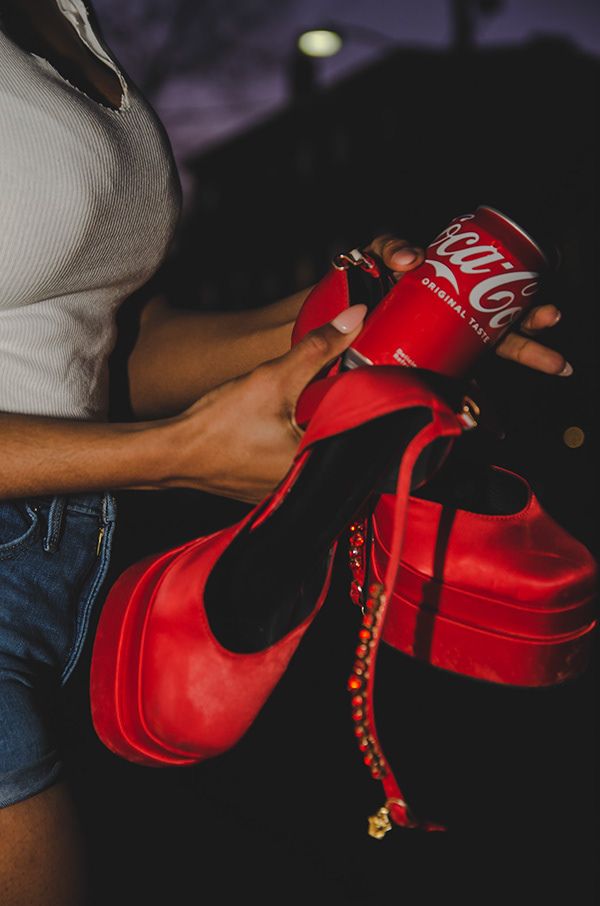 a girl holding coca-cola or coke with red heels