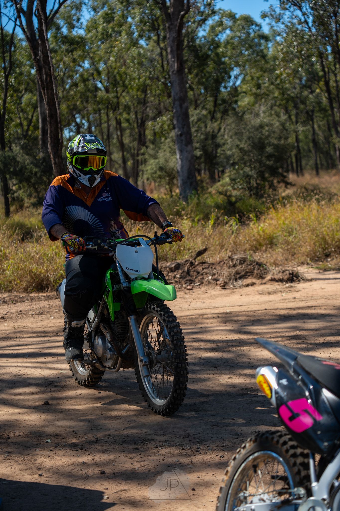 Motorcycle rider navigating a dirt trail through eucalyptus forest during off-road adventure.