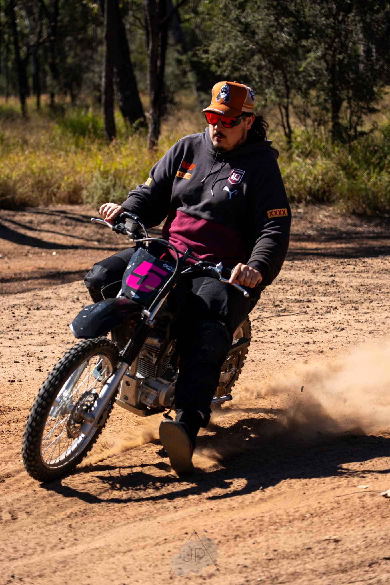 A series of sequential action shots showing a motorcycle rider performing a dirt slide maneuver on a dusty trail.