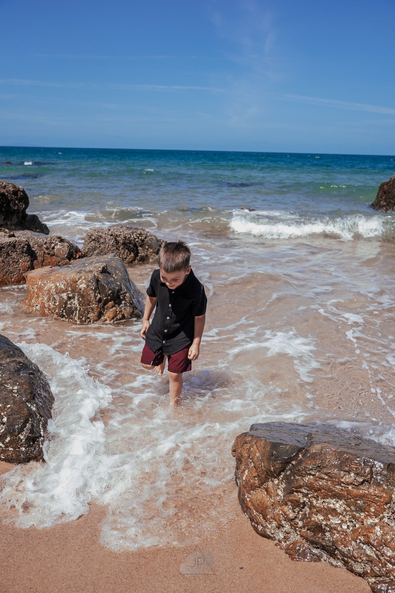 Sequence of photos showing waves crashing against rocky outcrops on a sandy beach under bright blue skies.