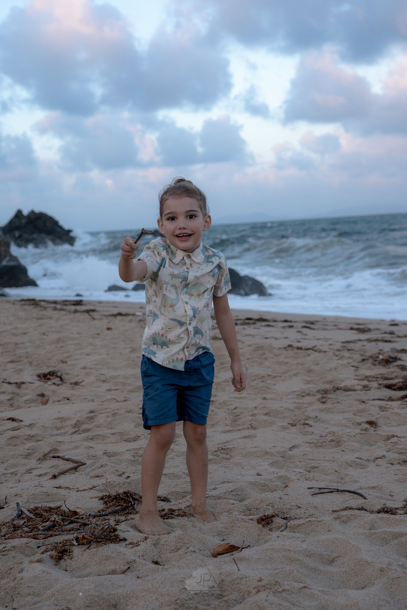 Young beachgoer exploring the sandy shoreline on an overcast day with waves crashing nearby.