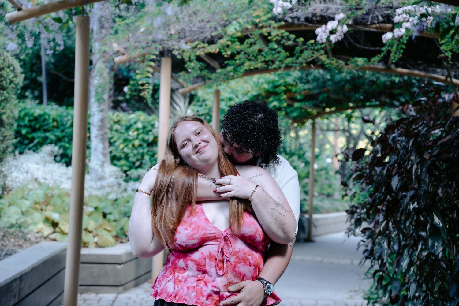 A couple shares tender moments together in a lush garden setting during a romantic outdoor photoshoot.