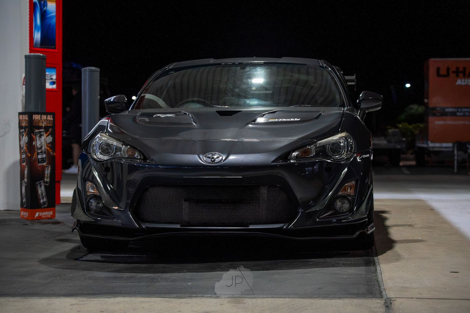 A sleek black Toyota GT86 sports car parked in a dimly lit garage or showroom space.
