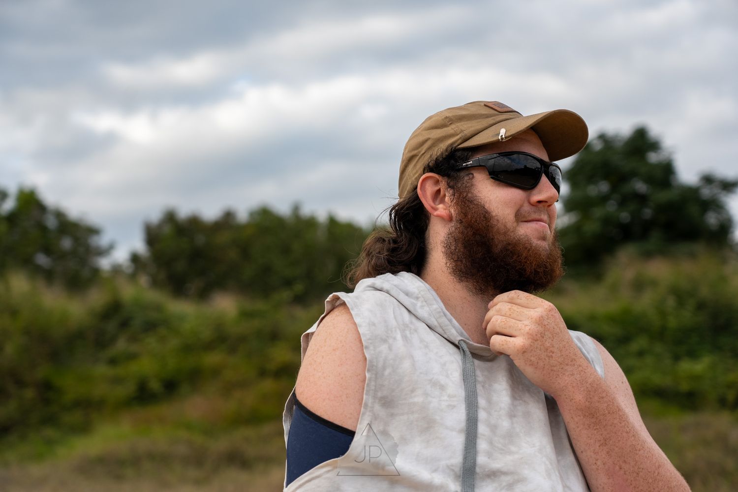 Fisherman in sunglasses and baseball cap smiling while enjoying a day outdoors on the water.