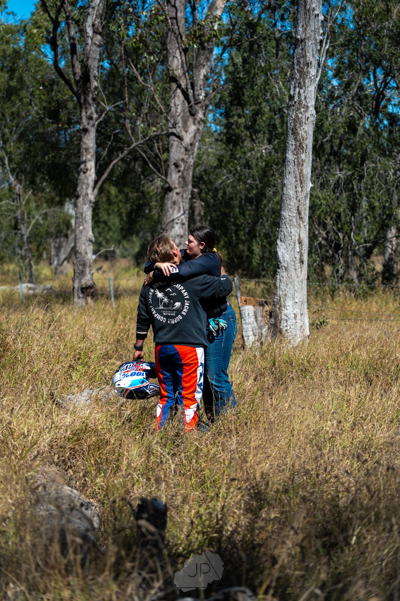 Two riders share a quiet moment together on a hillside beneath towering eucalyptus trees.